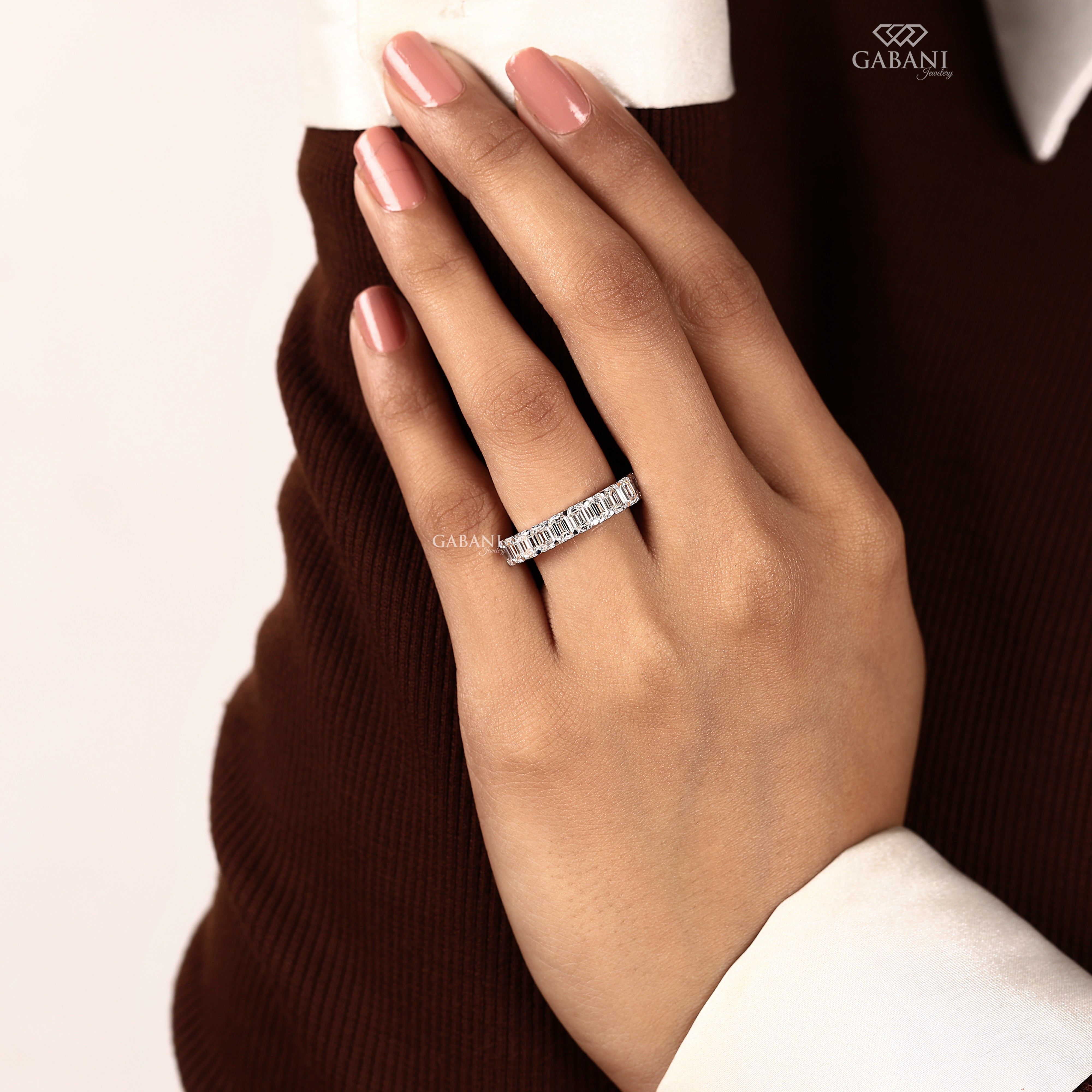 Hand model wearing an emerald cut lab grown diamond half eternity band with a clean and elegant bridal