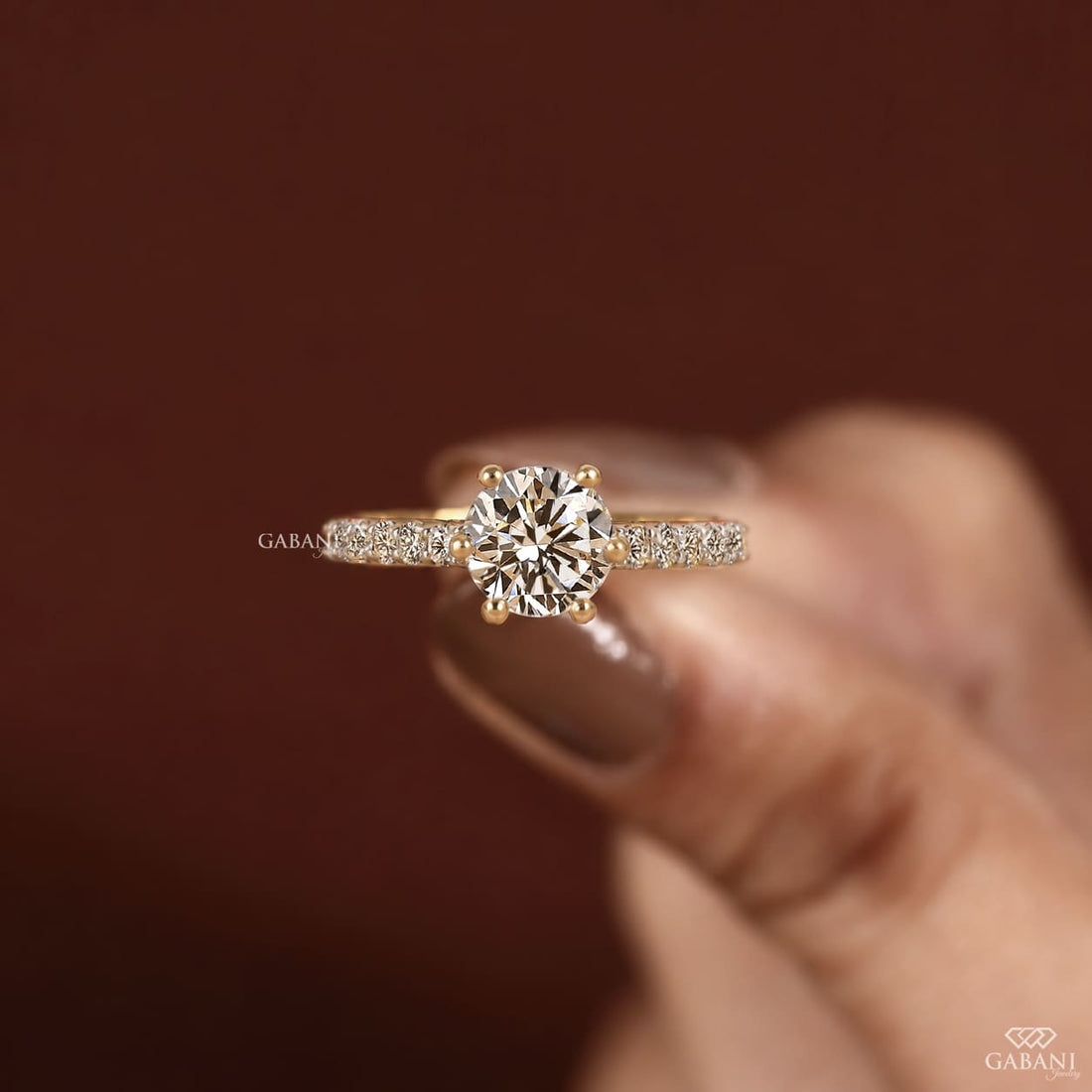 Round cut lab grown diamond solitaire engagement ring in yellow gold featuring a classic six prong setting and pavé diamond band.