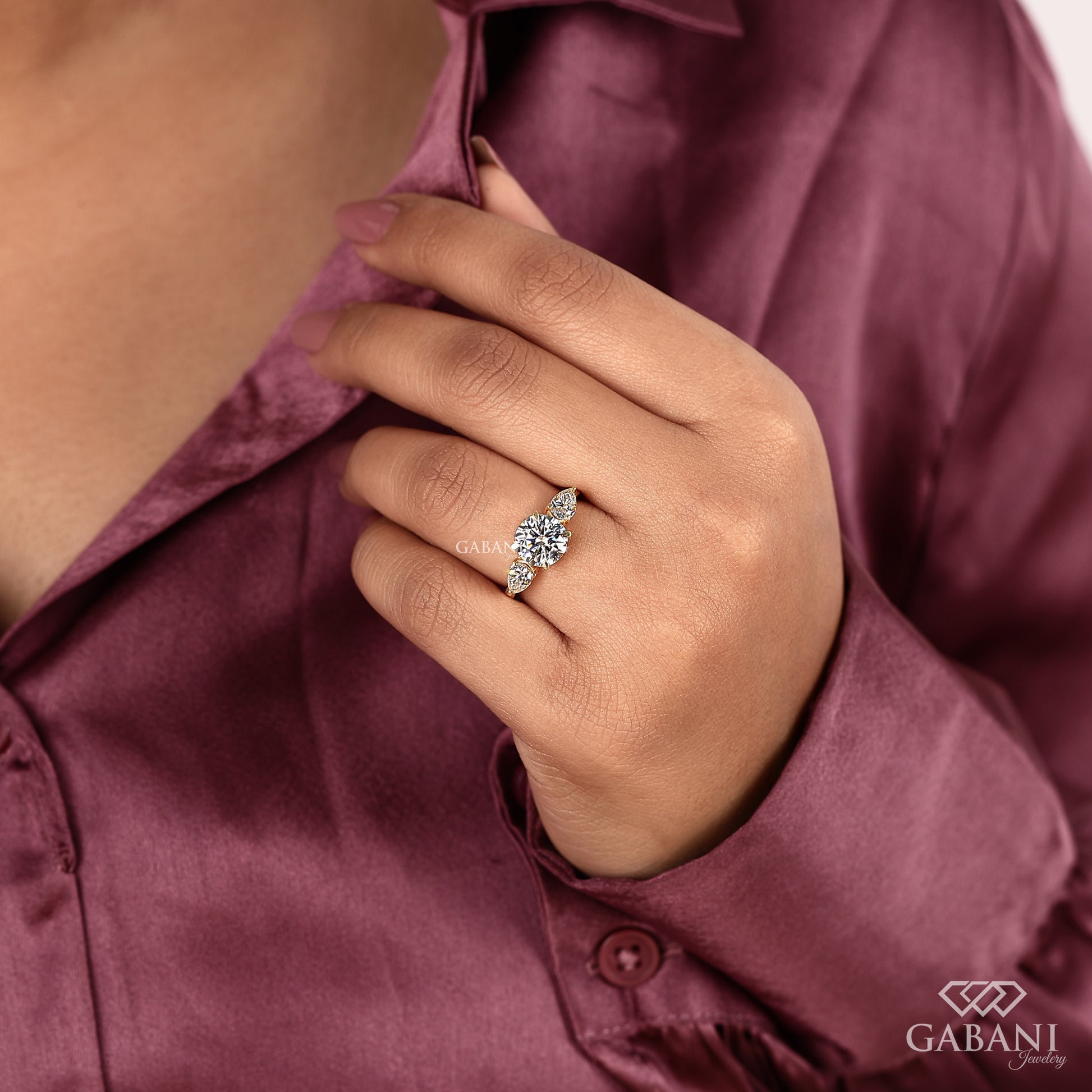 three stone lab grown diamond engagement ring with round center and pear sides in yellow gold