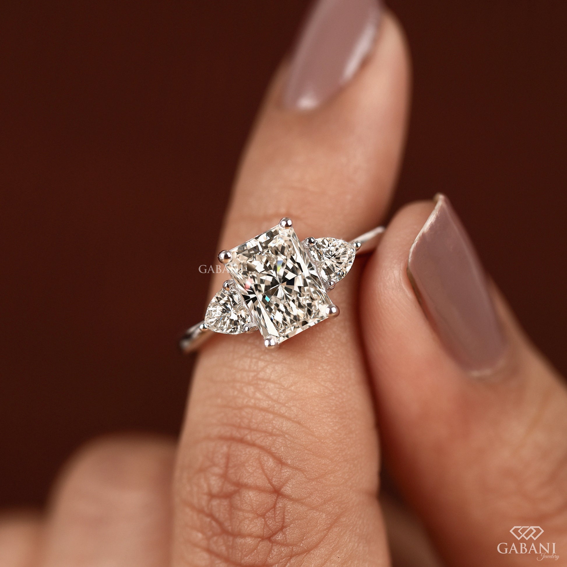 White gold three stone ring with radiant cut lab grown diamond and heart side accents