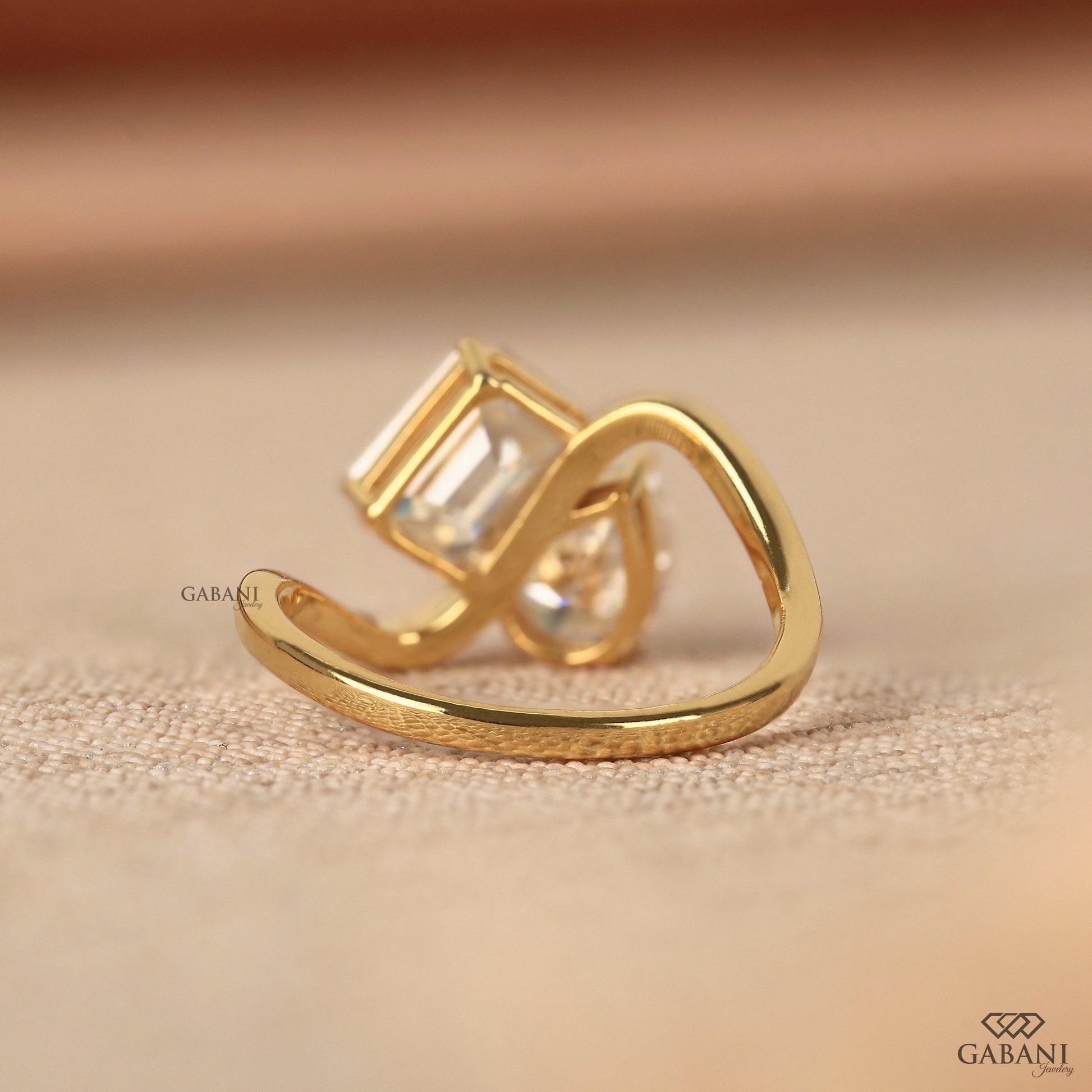 two stone lab grown diamond ring with emerald cut and pear cut stones in yellow gold