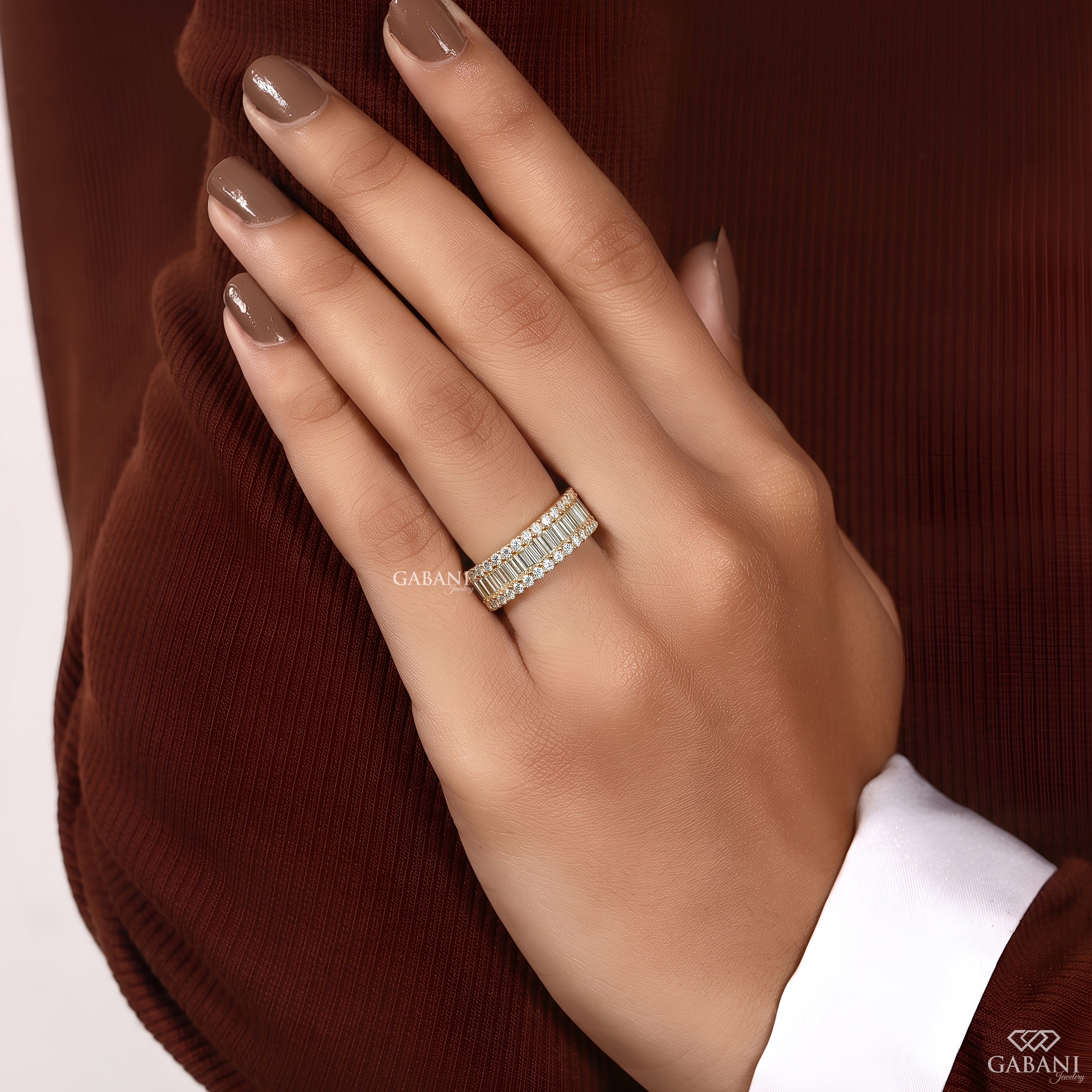 Model wearing a wide yellow gold baguette and round lab grown diamond wedding band on the engagement finger