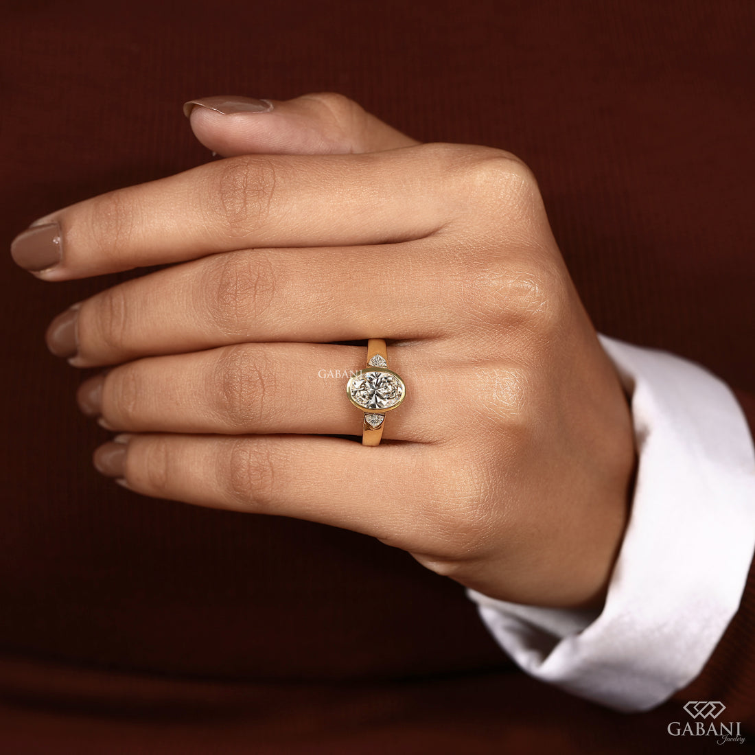 Gabani Jewelry oval cut lab grown diamond three stone engagement ring worn on a woman's hand