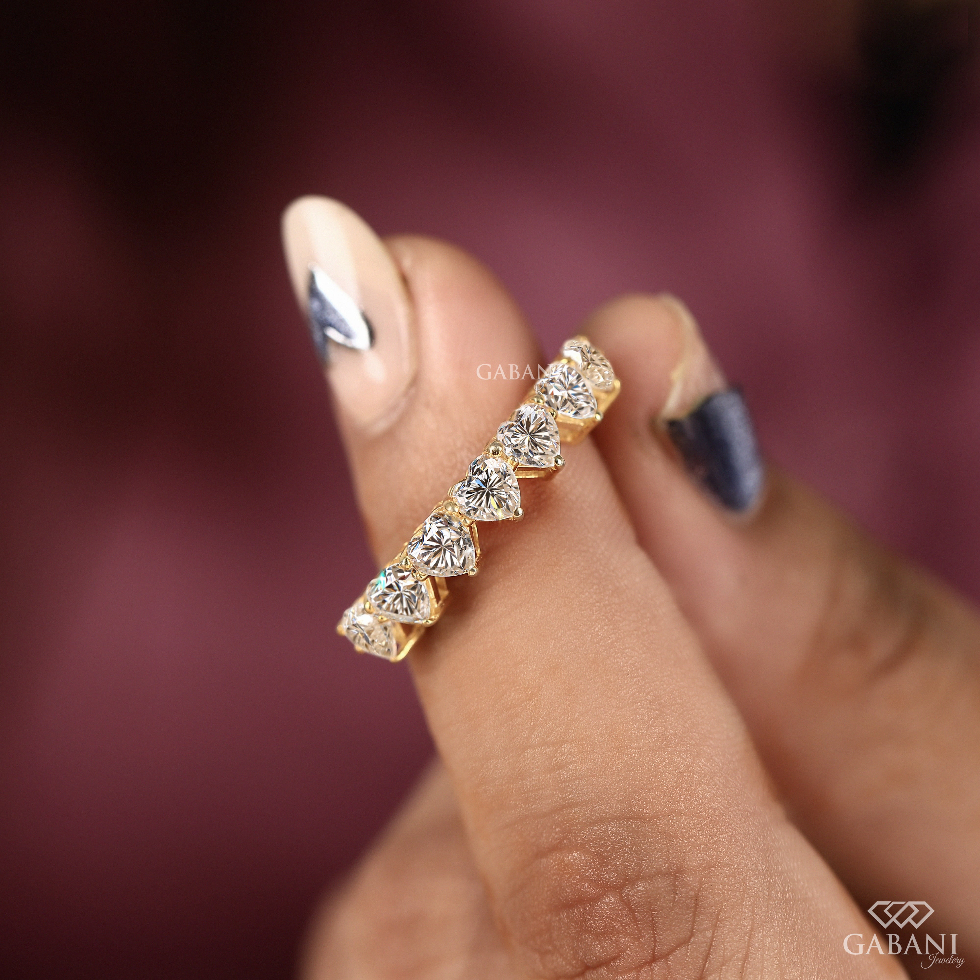 seven heart cut lab grown diamonds in a yellow gold half eternity wedding band with delicate prong settings.