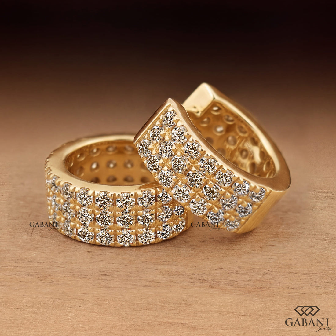 Yellow gold huggie hoop earrings with three rows of round diamonds across the front