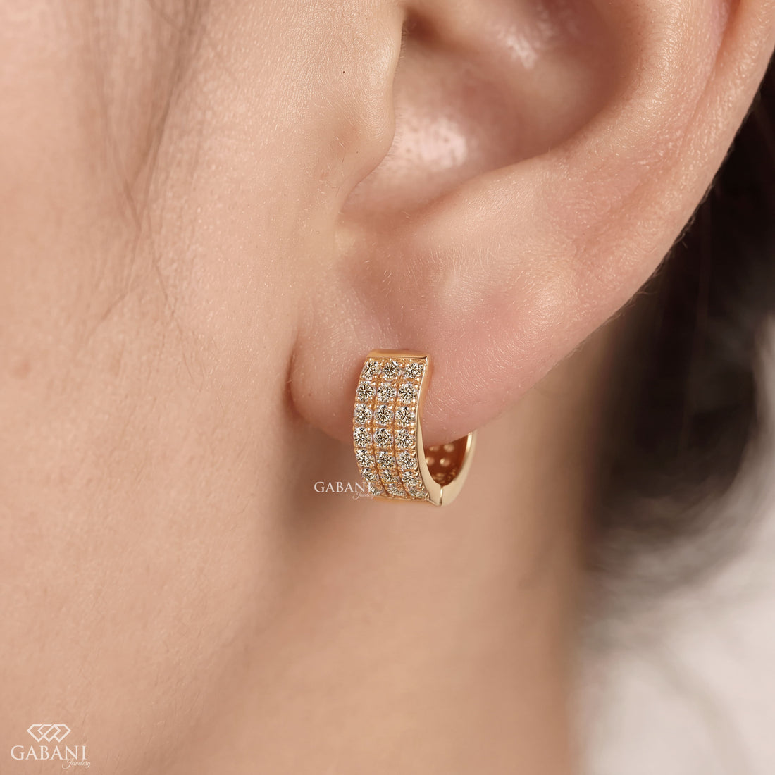 Yellow gold huggie hoop earrings with three rows of round diamonds across the front