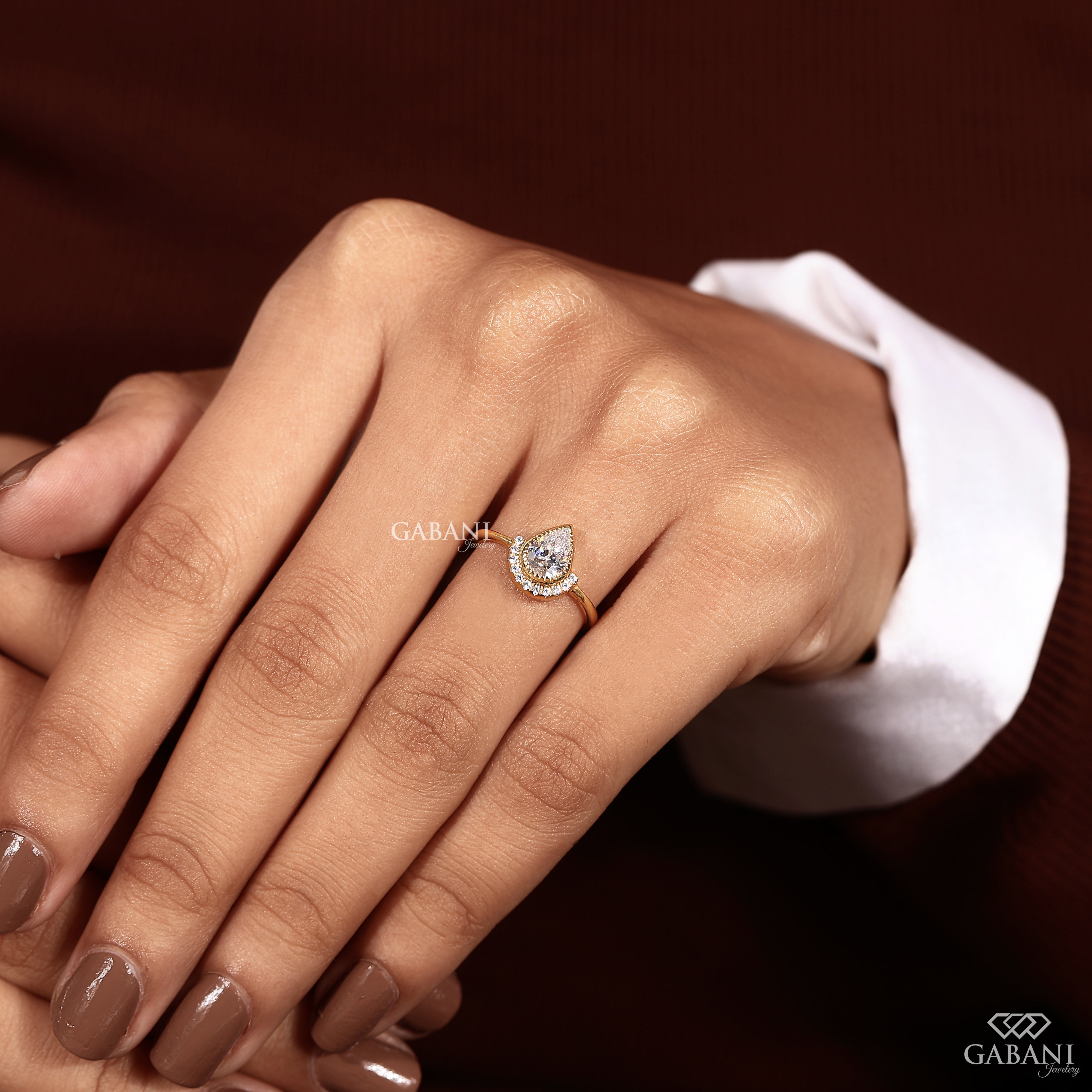 Yellow gold bezel set pear diamond engagement ring with round side diamonds