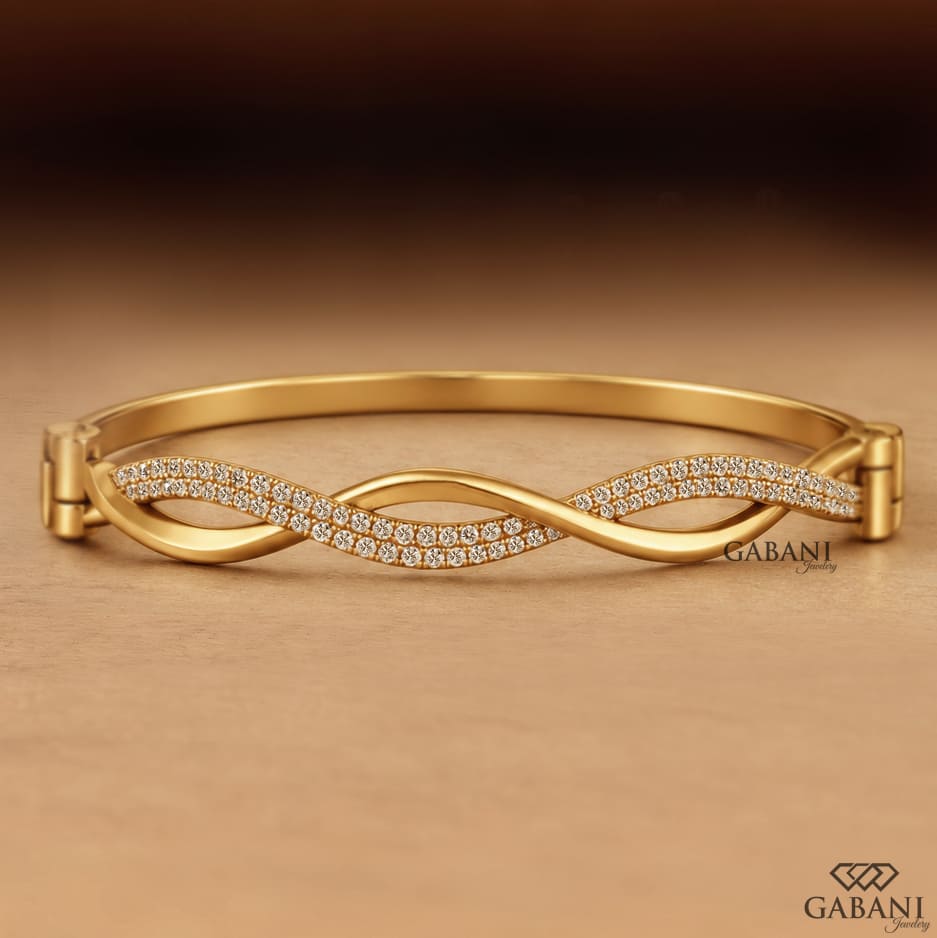 Yellow gold infinity twist bangle bracelet with intertwined polished bands and double rows of round pavé set diamonds.