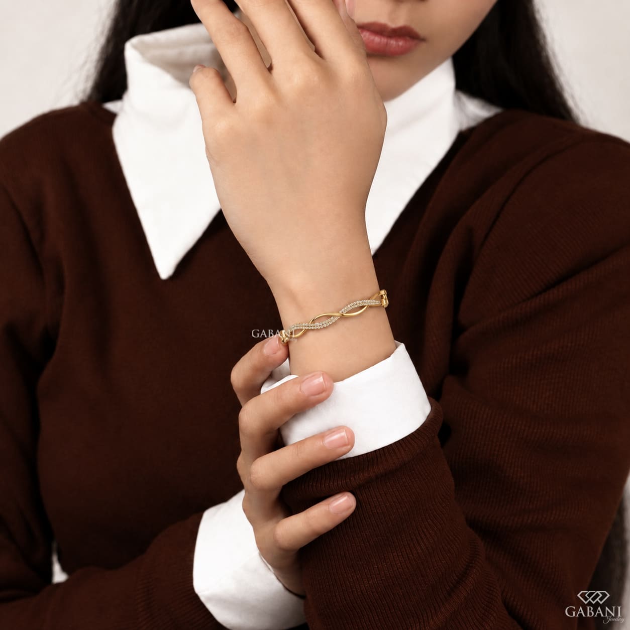 Yellow gold infinity twist bangle bracelet with intertwined polished bands and double rows of round pavé set diamonds.