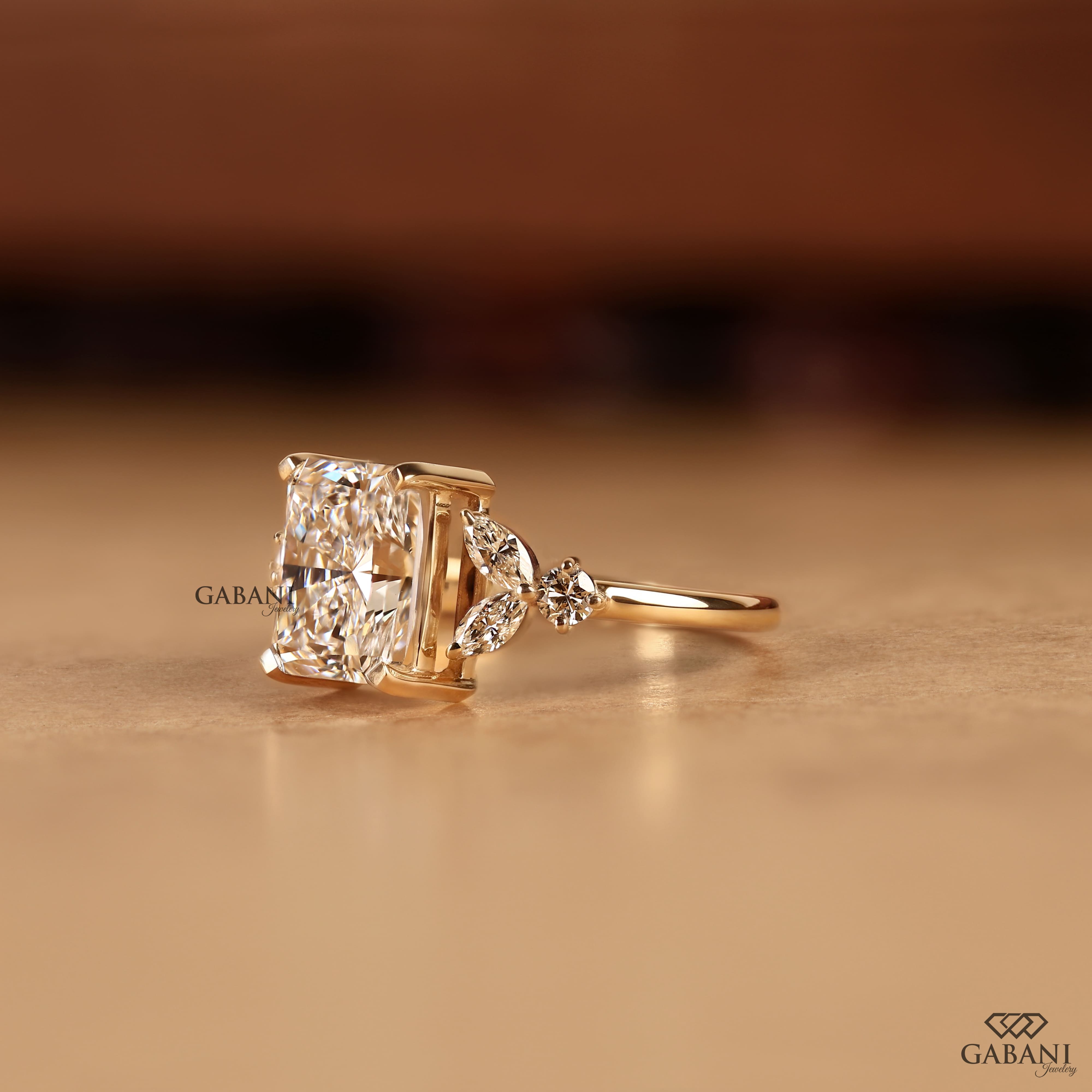 Radiant cut lab grown diamond engagement ring with marquise and round side diamond accents in a nature inspired gold setting.