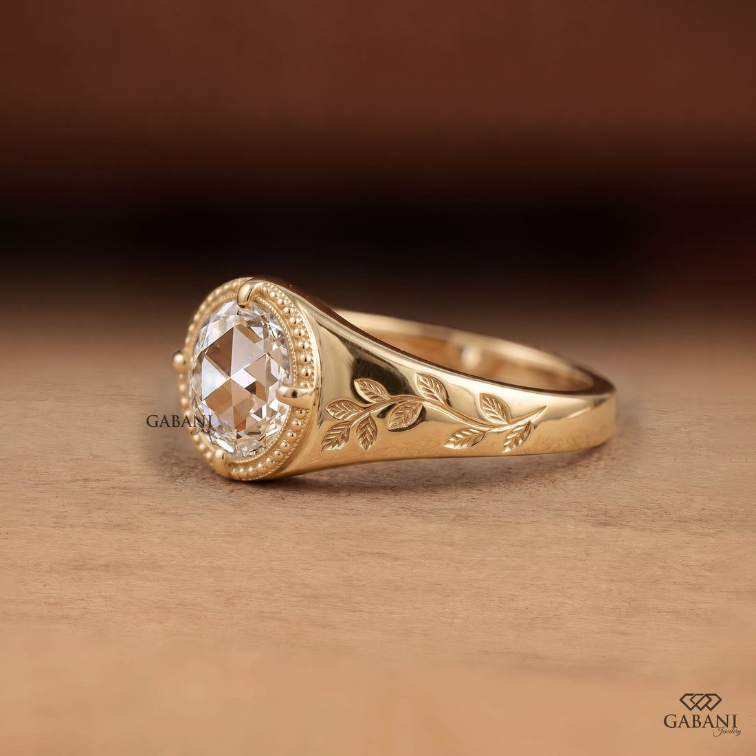 Round rose cut lab grown diamond signet ring with four prong setting, leaf engraving, beaded detailing and yellow gold band.