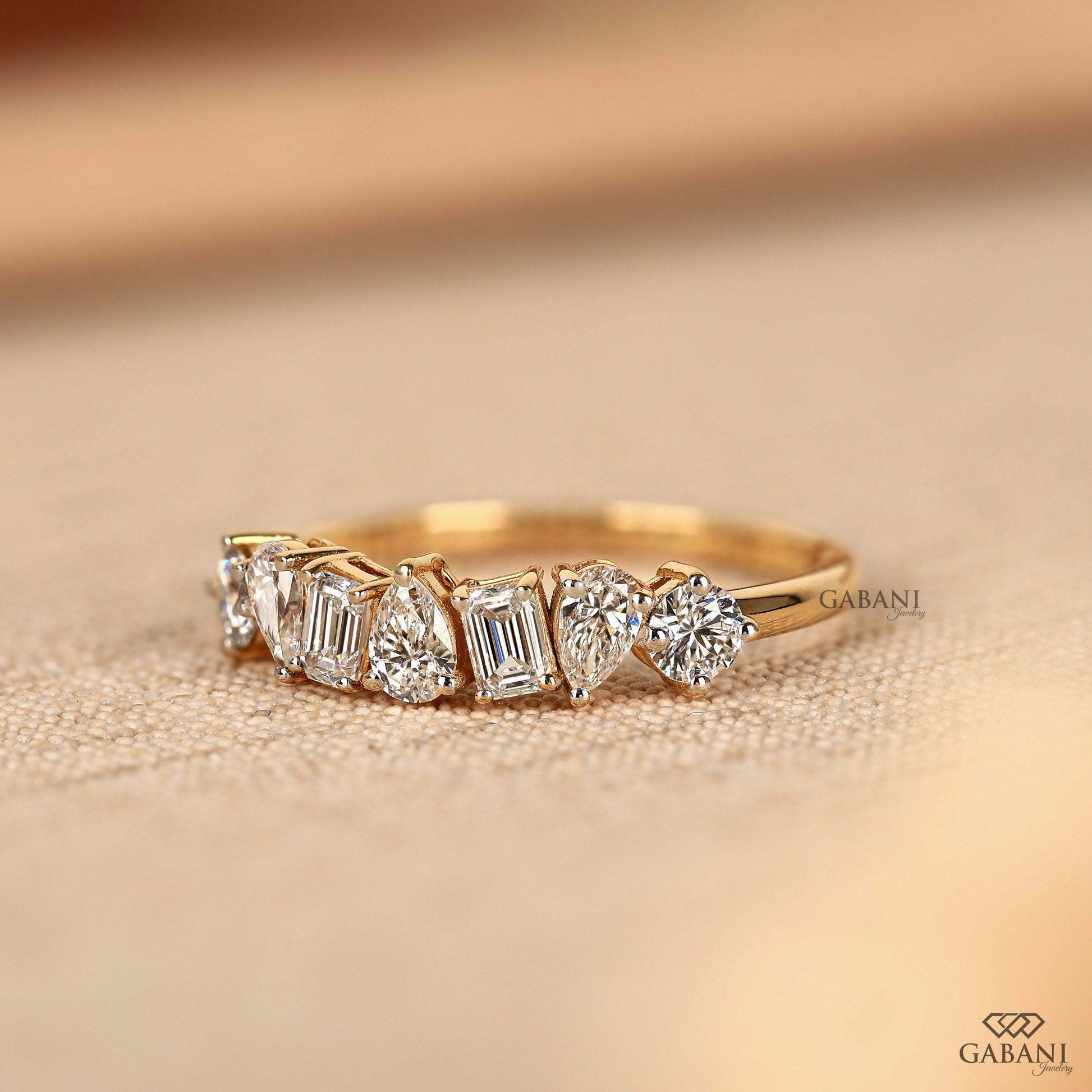 Prong set yellow gold band with emerald pear and round cut lab grown diamonds