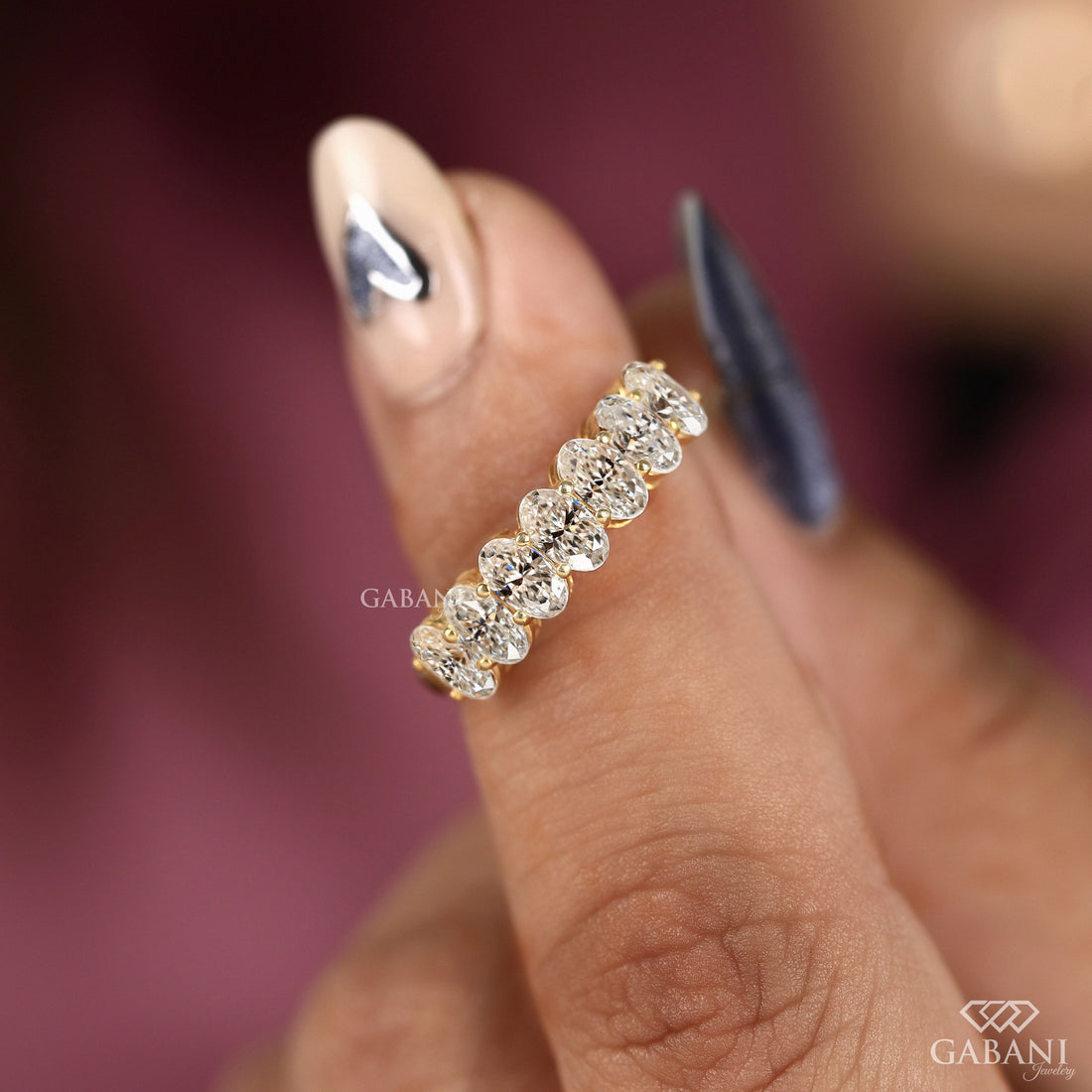 seven oval cut lab grown diamonds arranged in a prong set half eternity wedding band with polished 14K yellow gold.