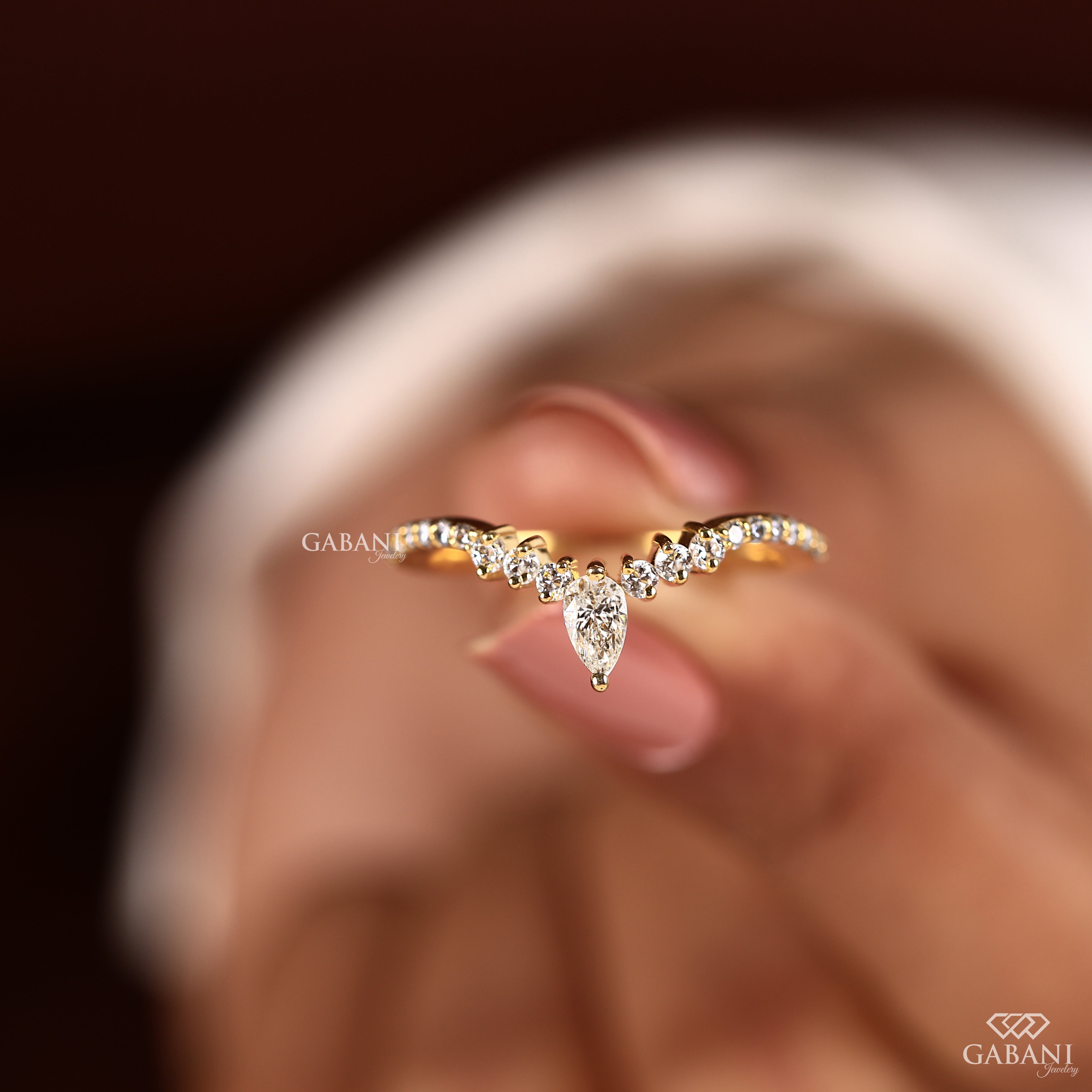 Holding a solid gold V shaped chevron wedding band with pear cut lab grown diamond