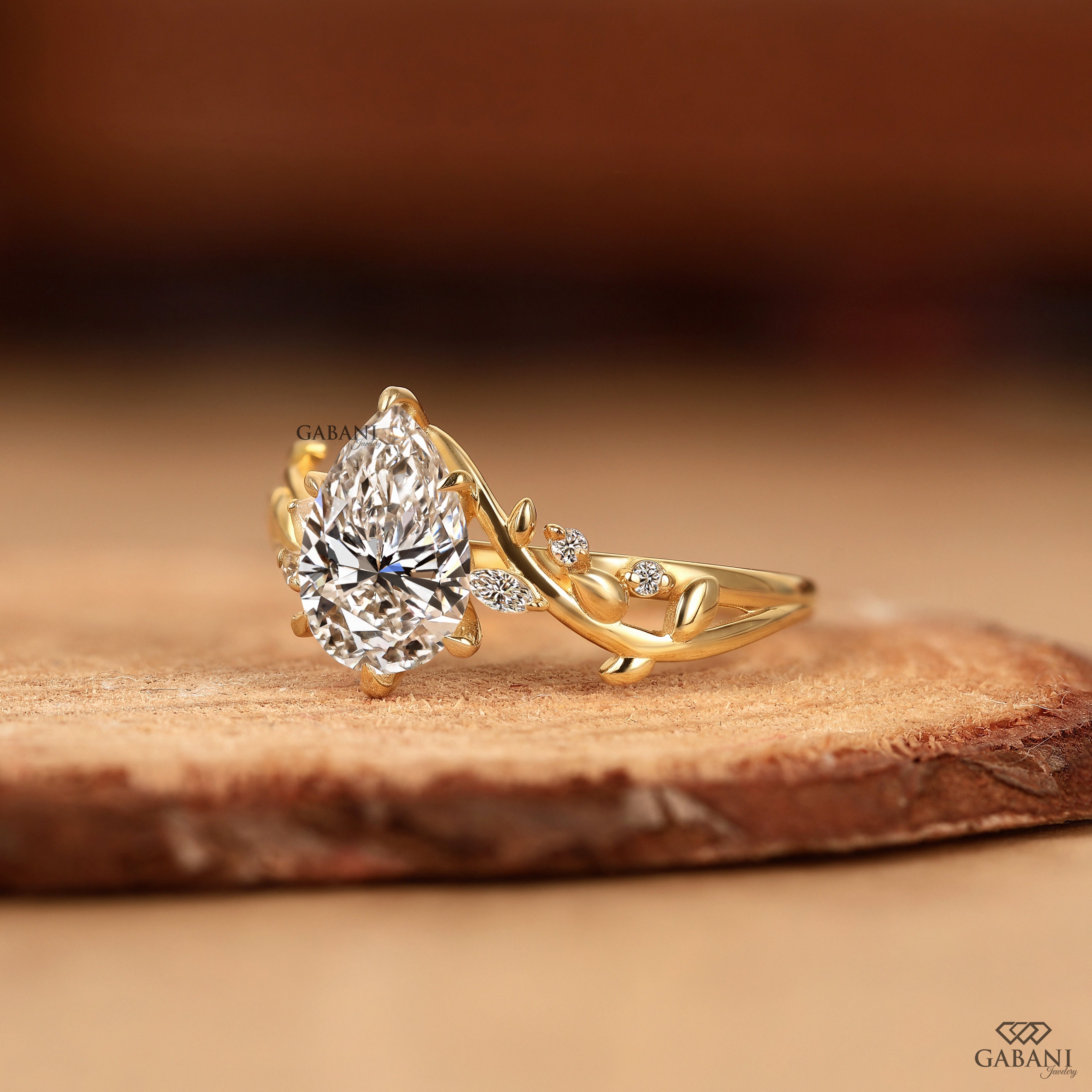 Pear cut lab grown diamond leaf style ring displayed on wood background