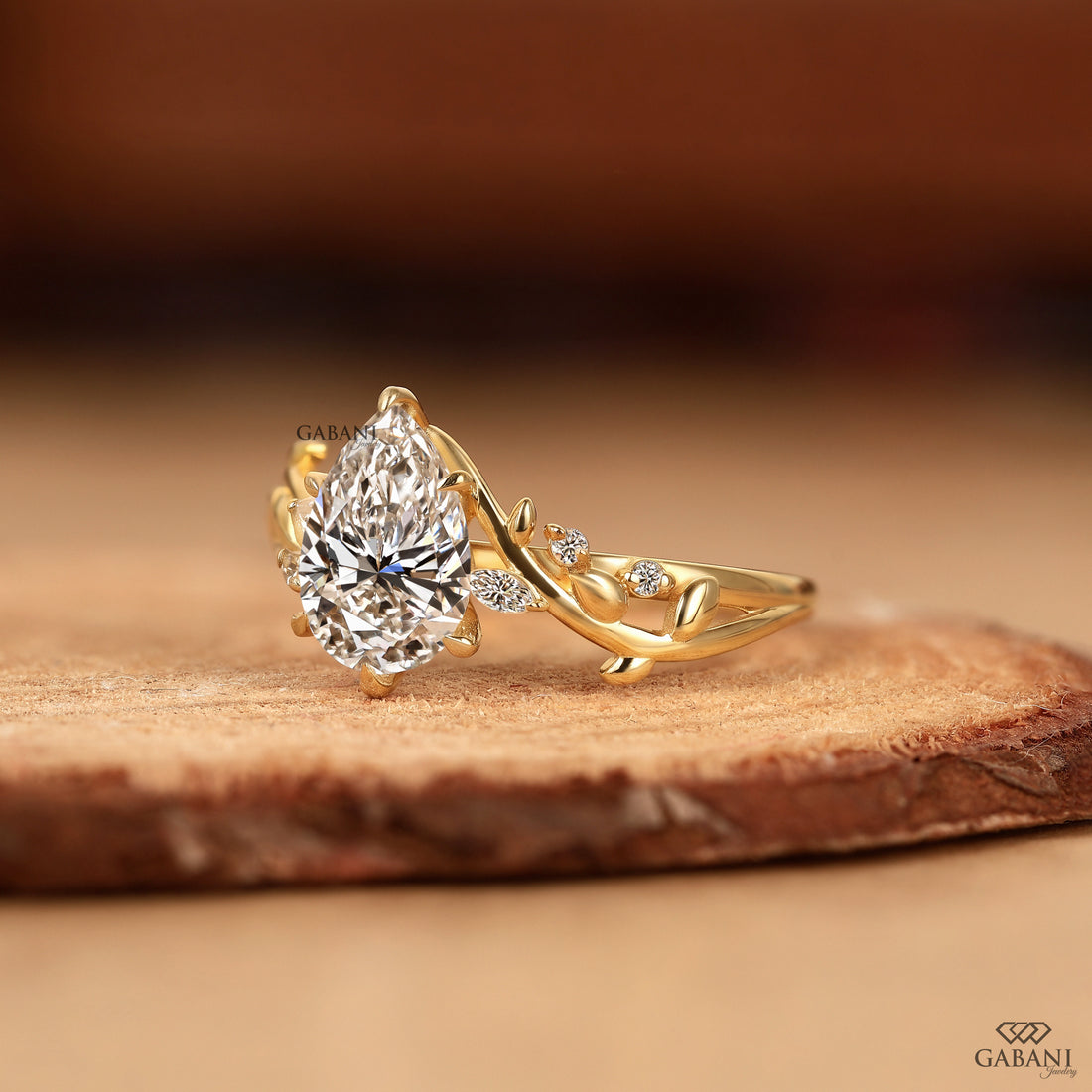 Pear cut lab grown diamond leaf style ring displayed on wood background