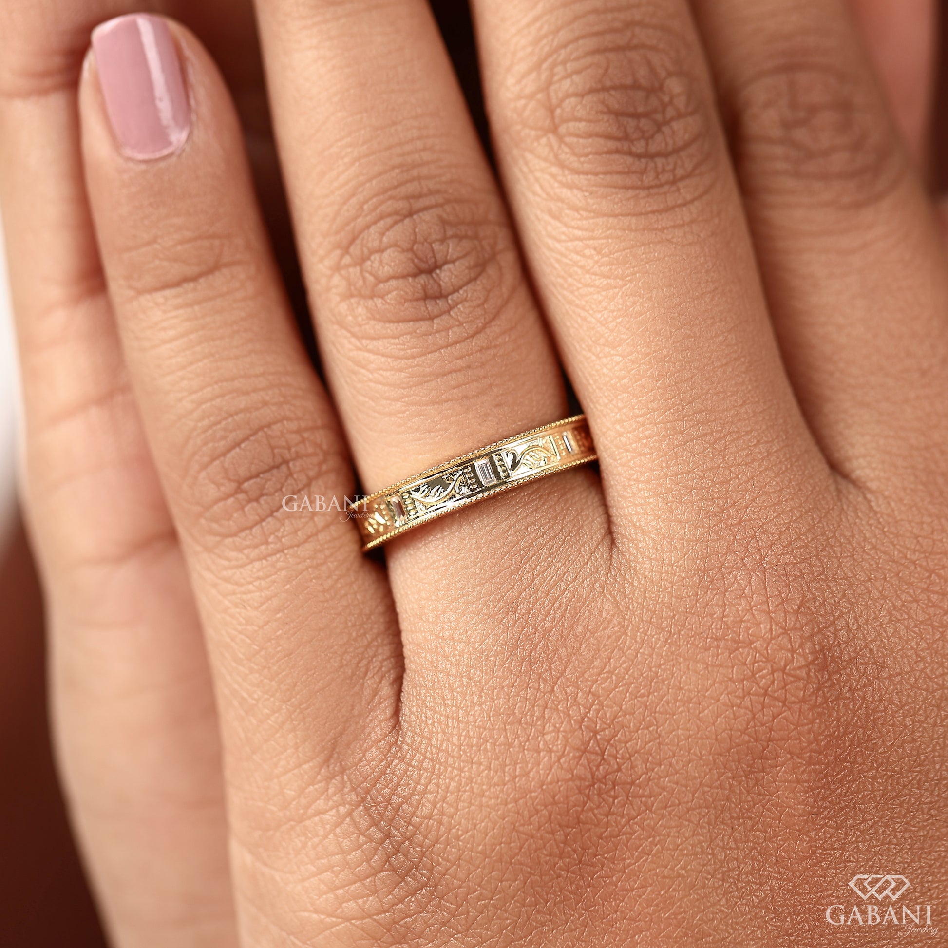 Close up of engraved leaf pattern on milgrain gold band with delicate diamond accents and fine handcrafted texture
