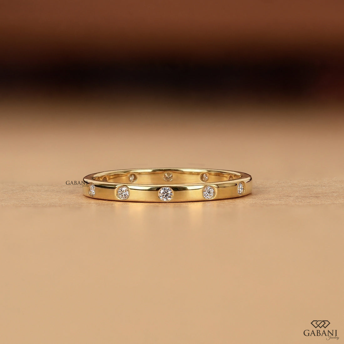 a minimalist lab grown diamond wedding band featuring round cut diamonds individually flush set into polished 14K yellow gold, creating a modern eternity ring perfect for bridal stacking.