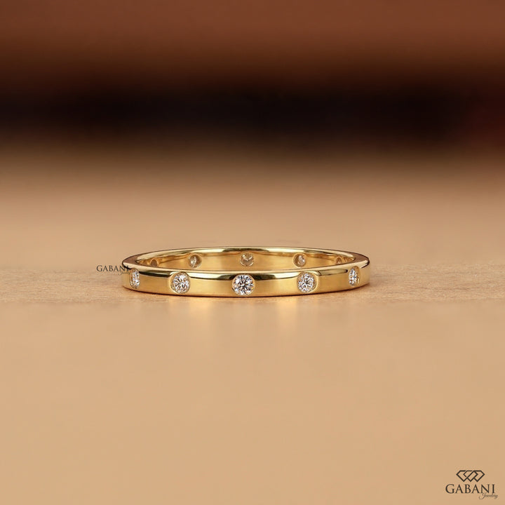 a minimalist lab grown diamond wedding band featuring round cut diamonds individually flush set into polished 14K yellow gold, creating a modern eternity ring perfect for bridal stacking.