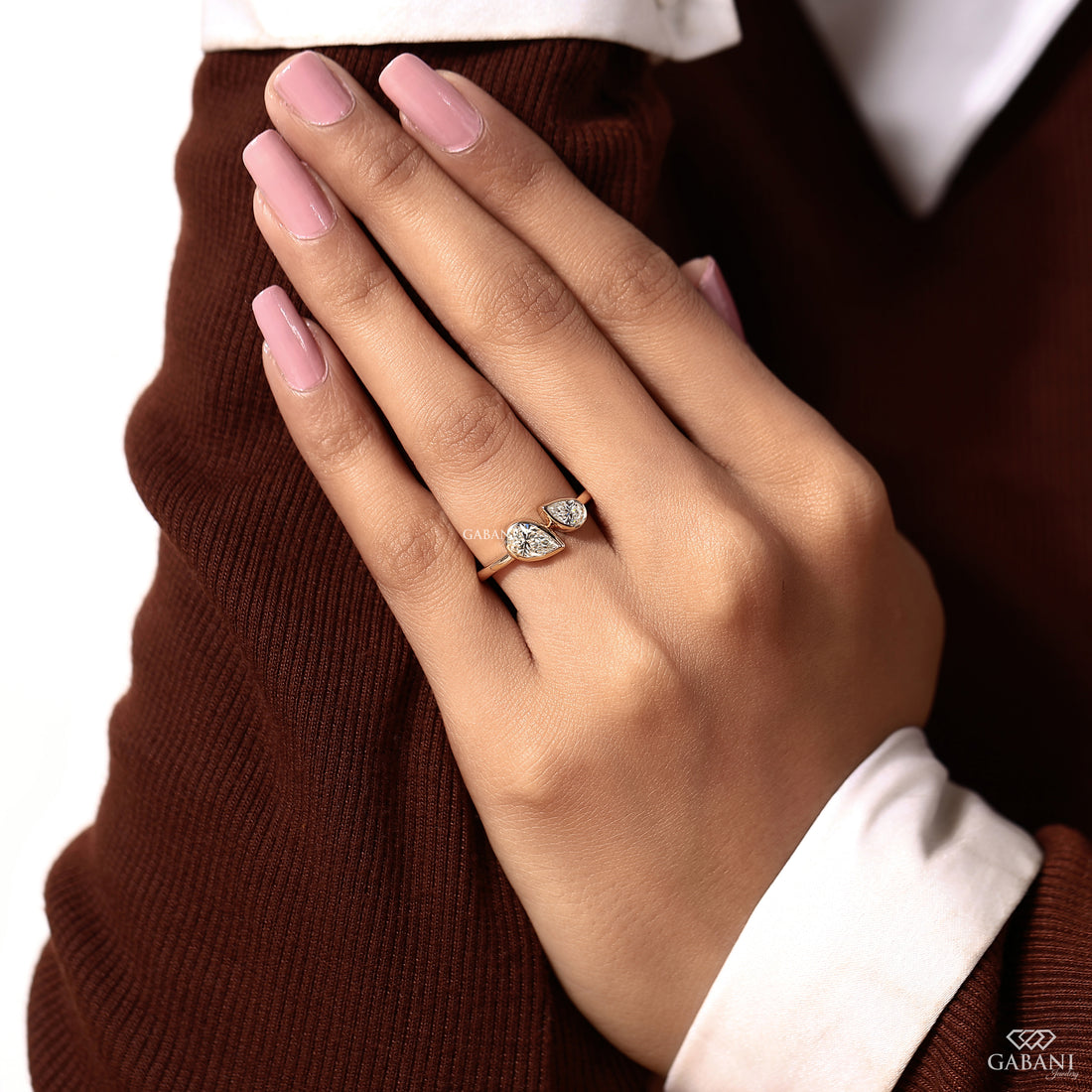 Hand model wearing a Gabani Jewelry pear cut lab grown diamond Toi et Moi engagement ring with bezel set diamonds