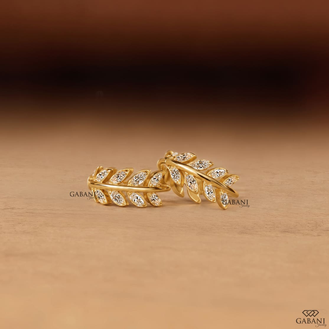 Marquise diamond leaf huggie earrings in yellow gold with a nature inspired vine design and marquise cut diamond leaves.