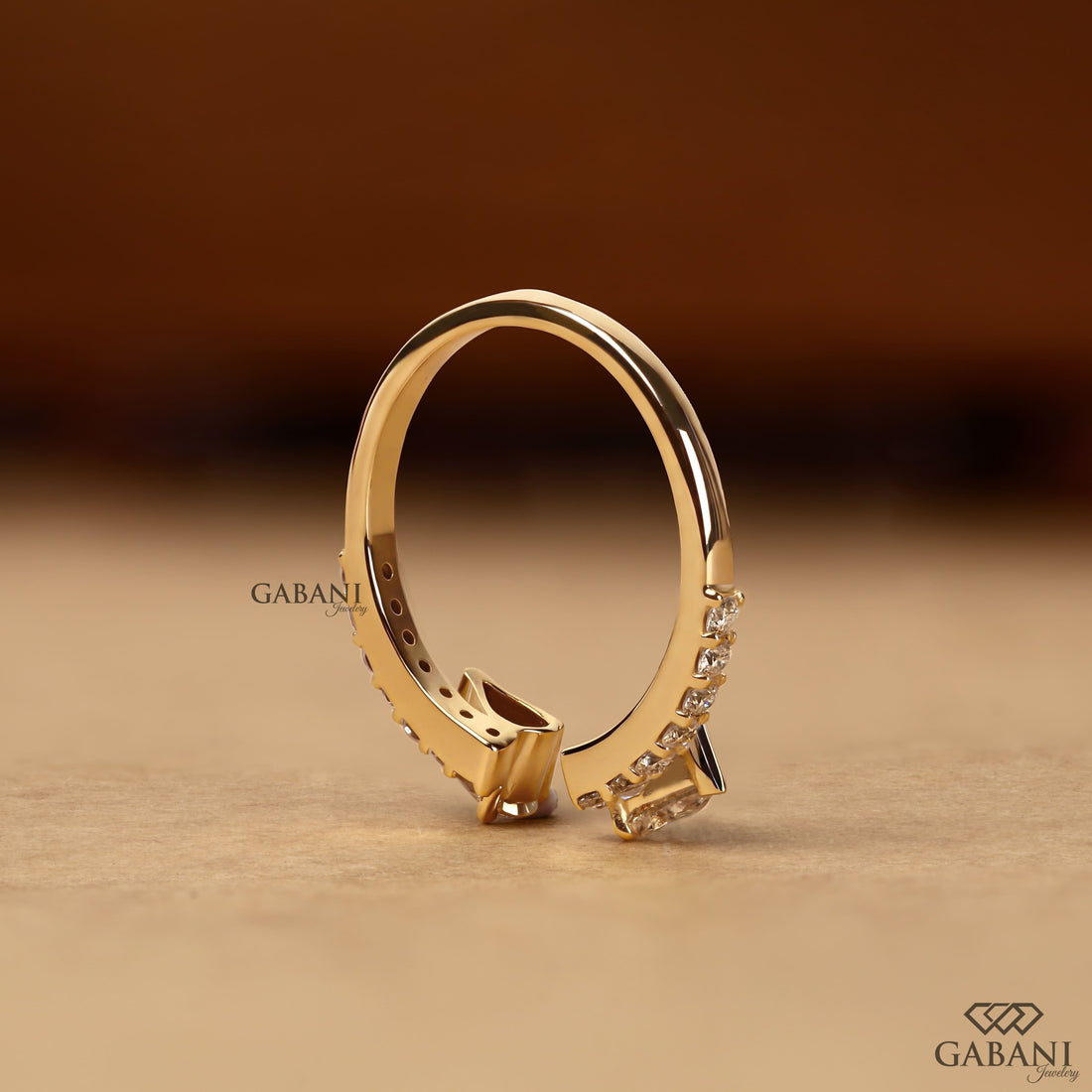 pear cut lab grown diamond open cuff ring showing the partial bezel settings, open ends and polished yellow gold band.