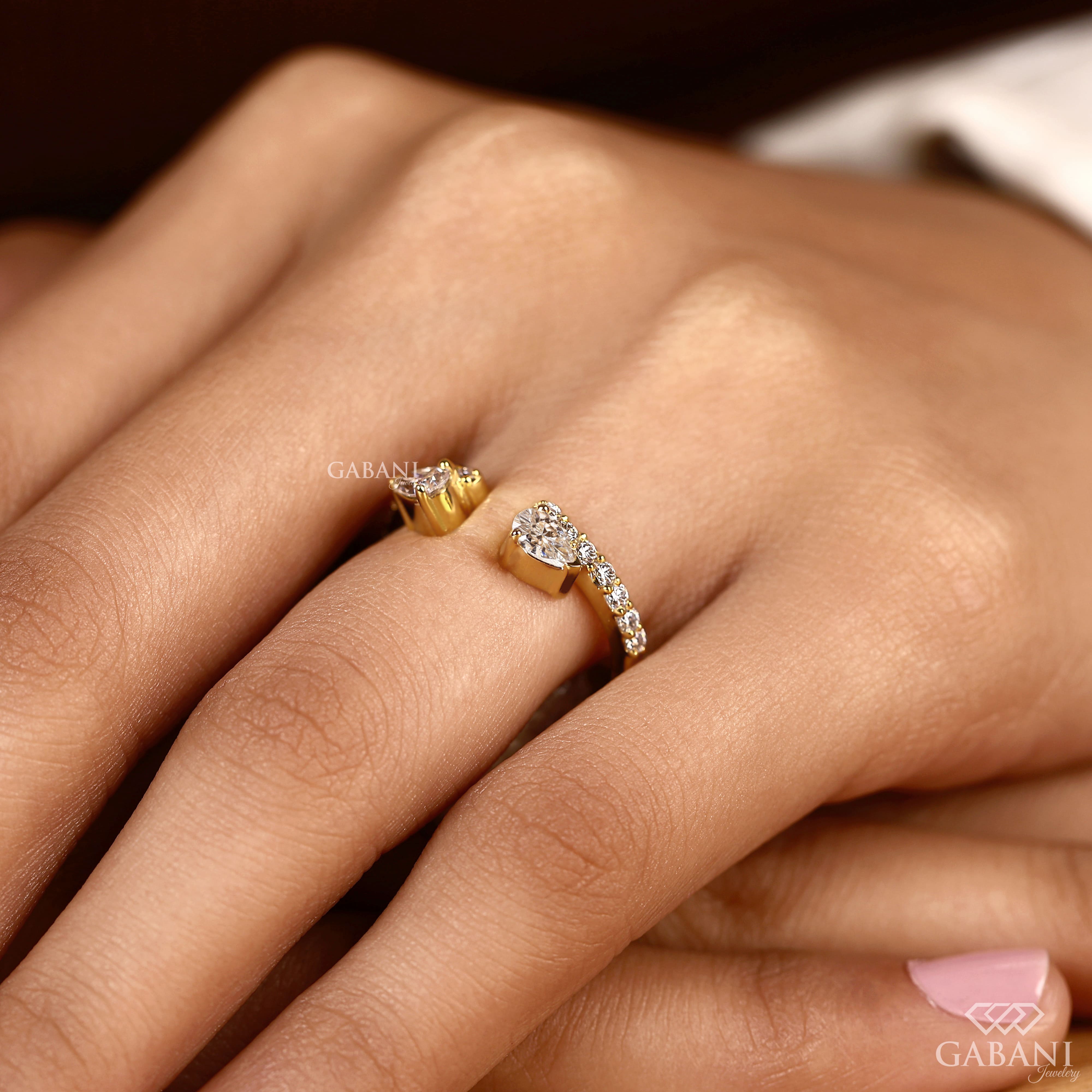 pear cut lab grown diamond open cuff ring showing the partial bezel settings, open ends and polished yellow gold band.