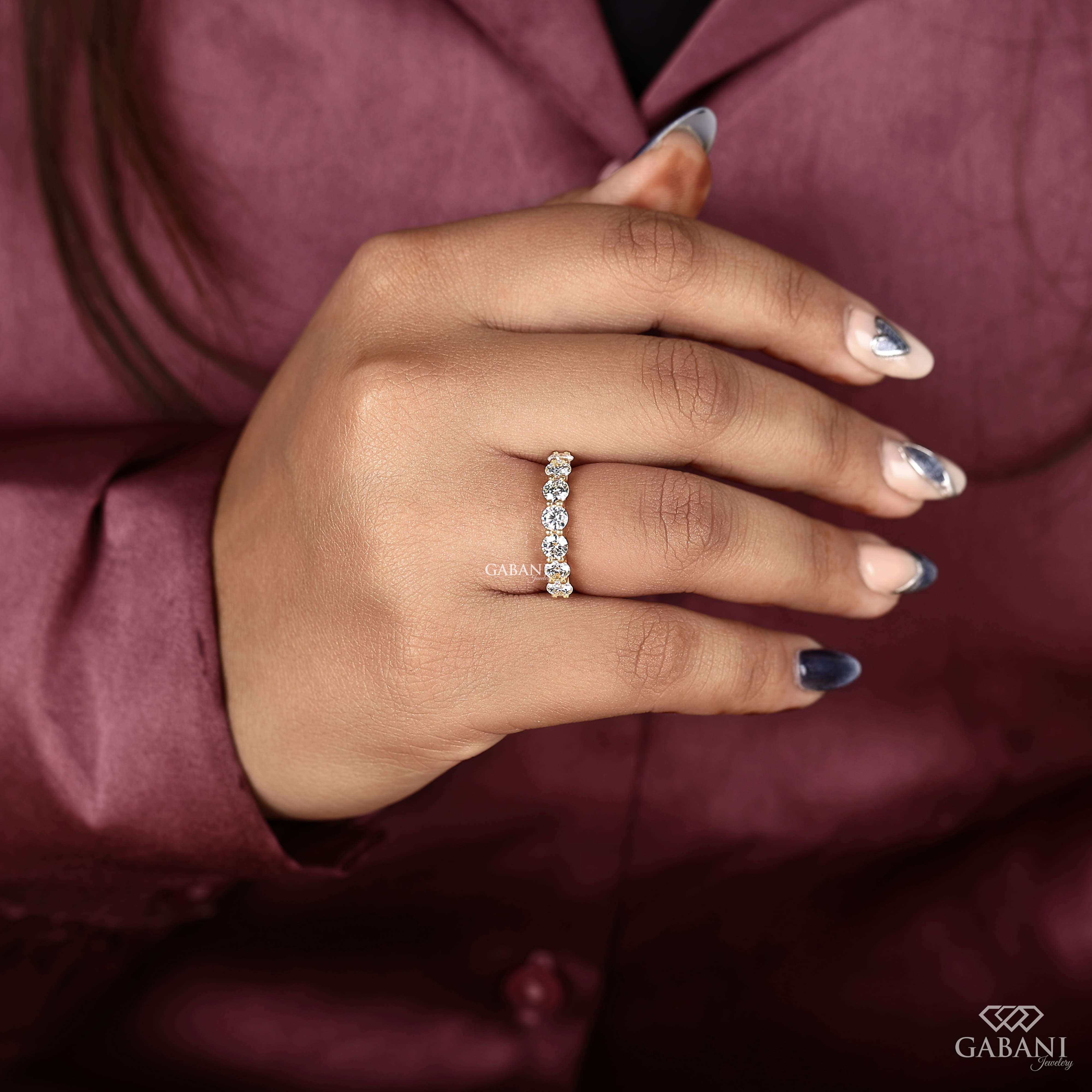 seven round cut lab grown diamonds in a yellow gold half eternity wedding band with open prong settings and a smooth shank.