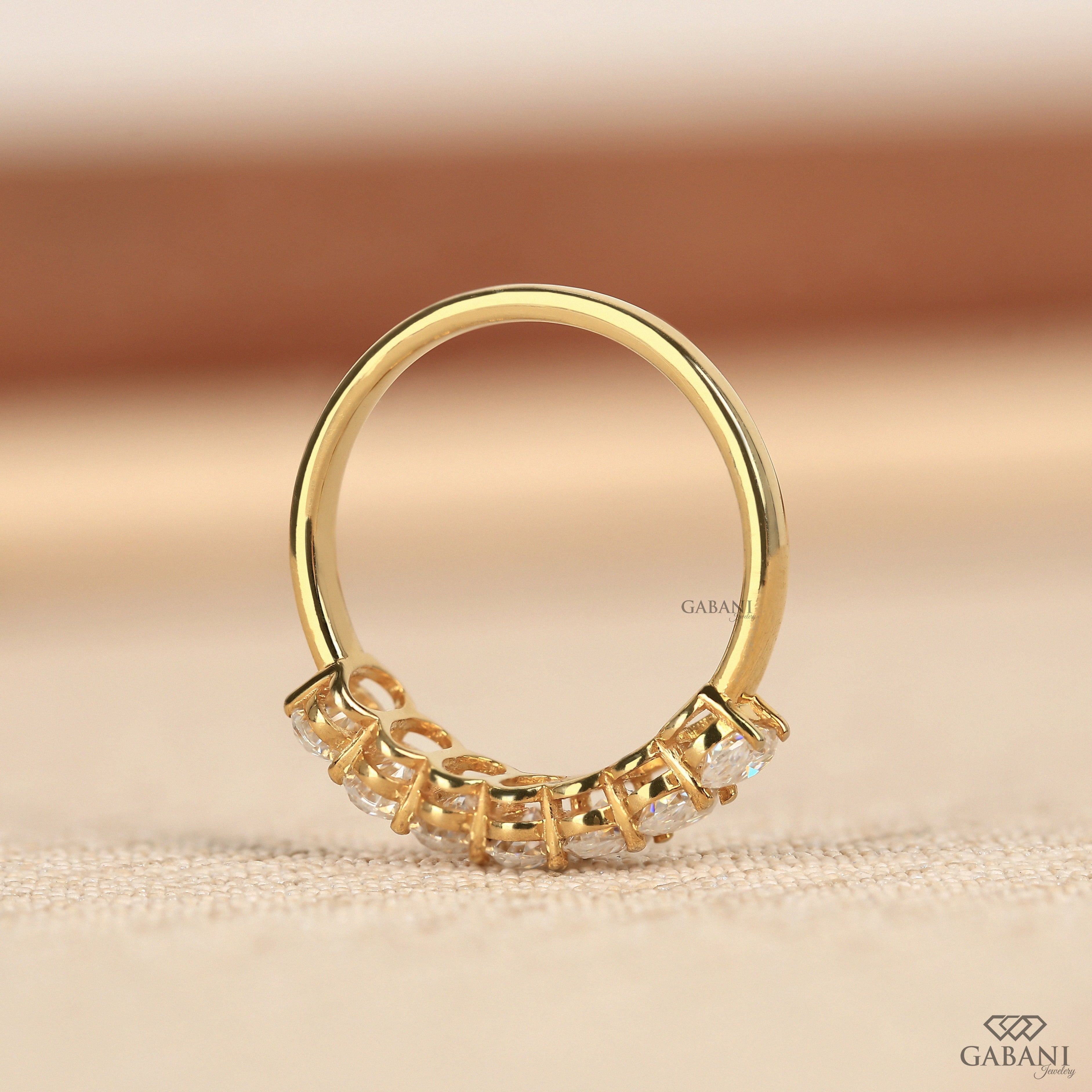 seven oval cut lab grown diamonds arranged in a prong set half eternity wedding band with polished 14K yellow gold.