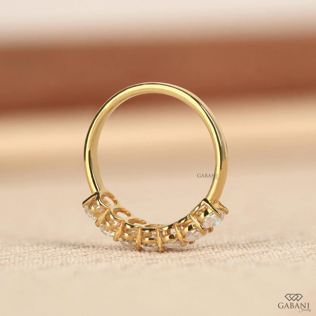 seven oval cut lab grown diamonds arranged in a prong set half eternity wedding band with polished 14K yellow gold.