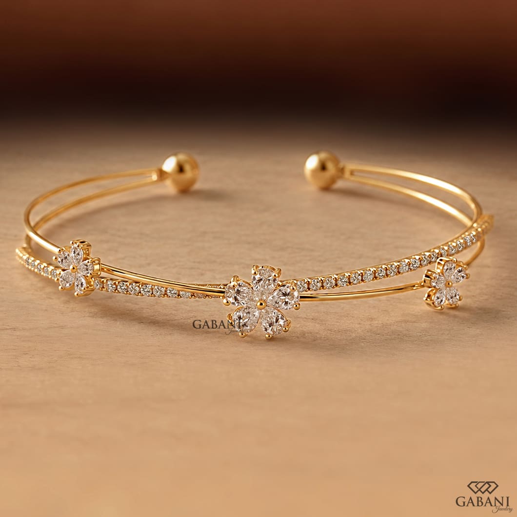 Yellow gold open cuff bangle bracelet featuring three pear cut diamond flower clusters and round pavé diamond accents.