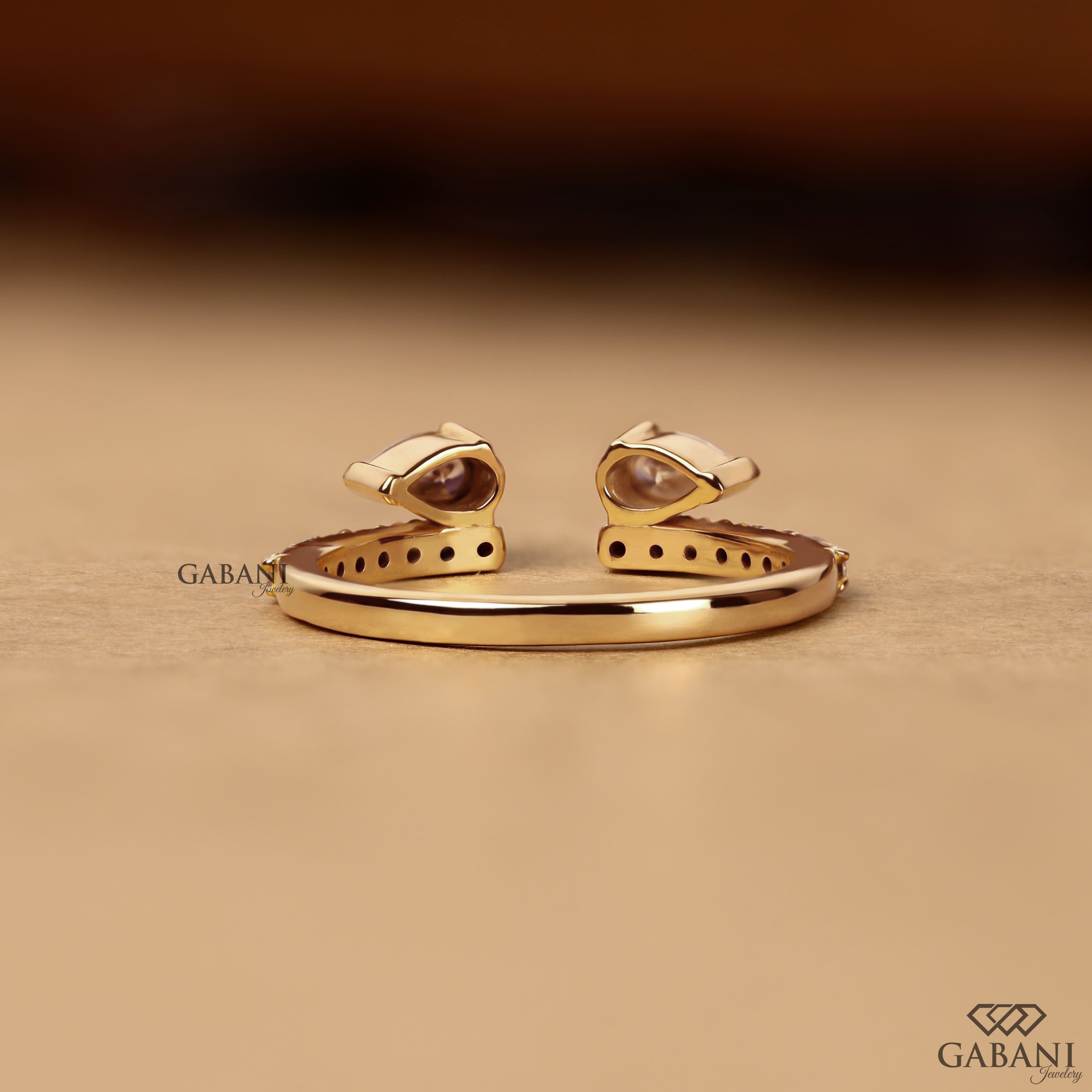 pear cut lab grown diamond open cuff ring showing the partial bezel settings, open ends and polished yellow gold band.