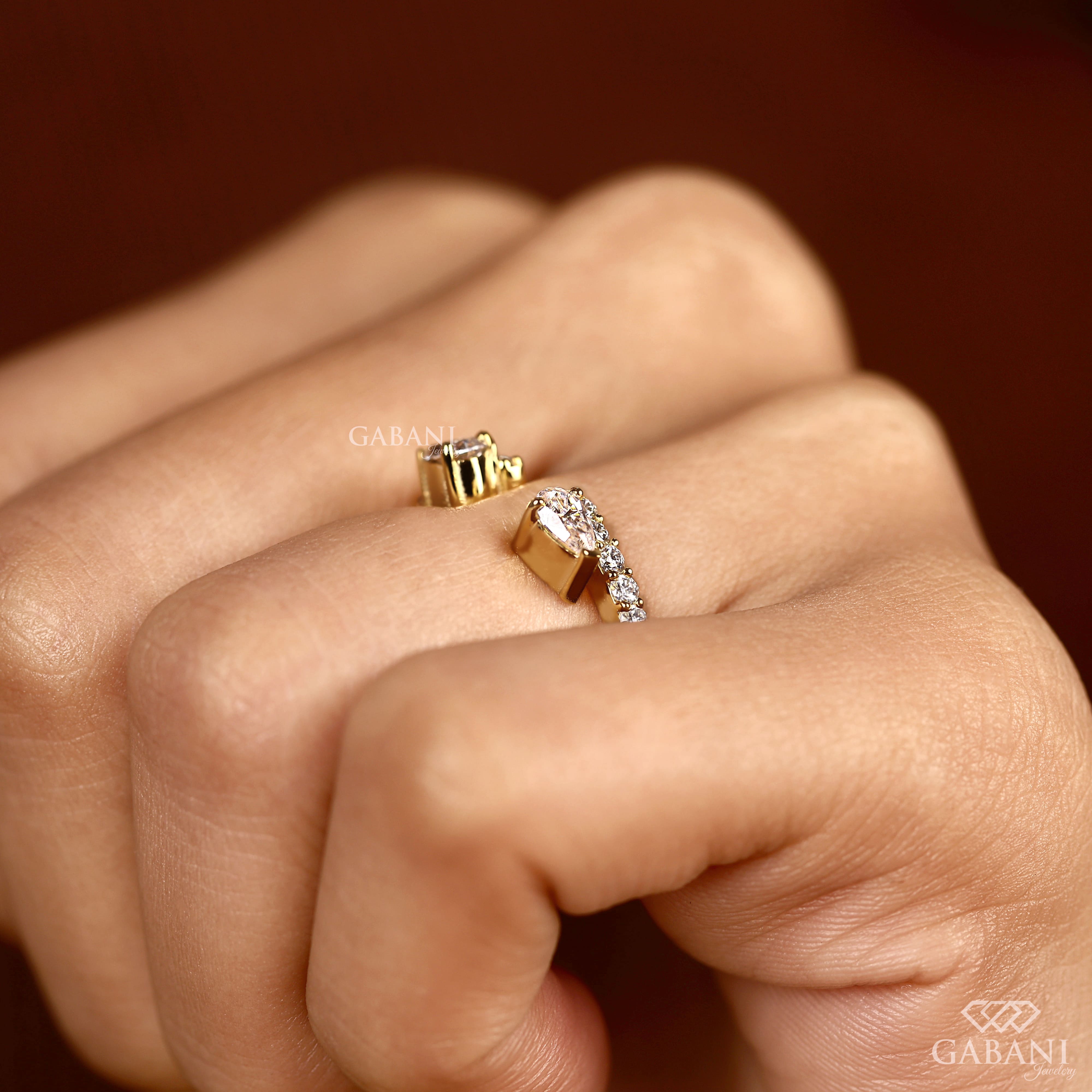 pear cut lab grown diamond open cuff ring showing the partial bezel settings, open ends and polished yellow gold band.