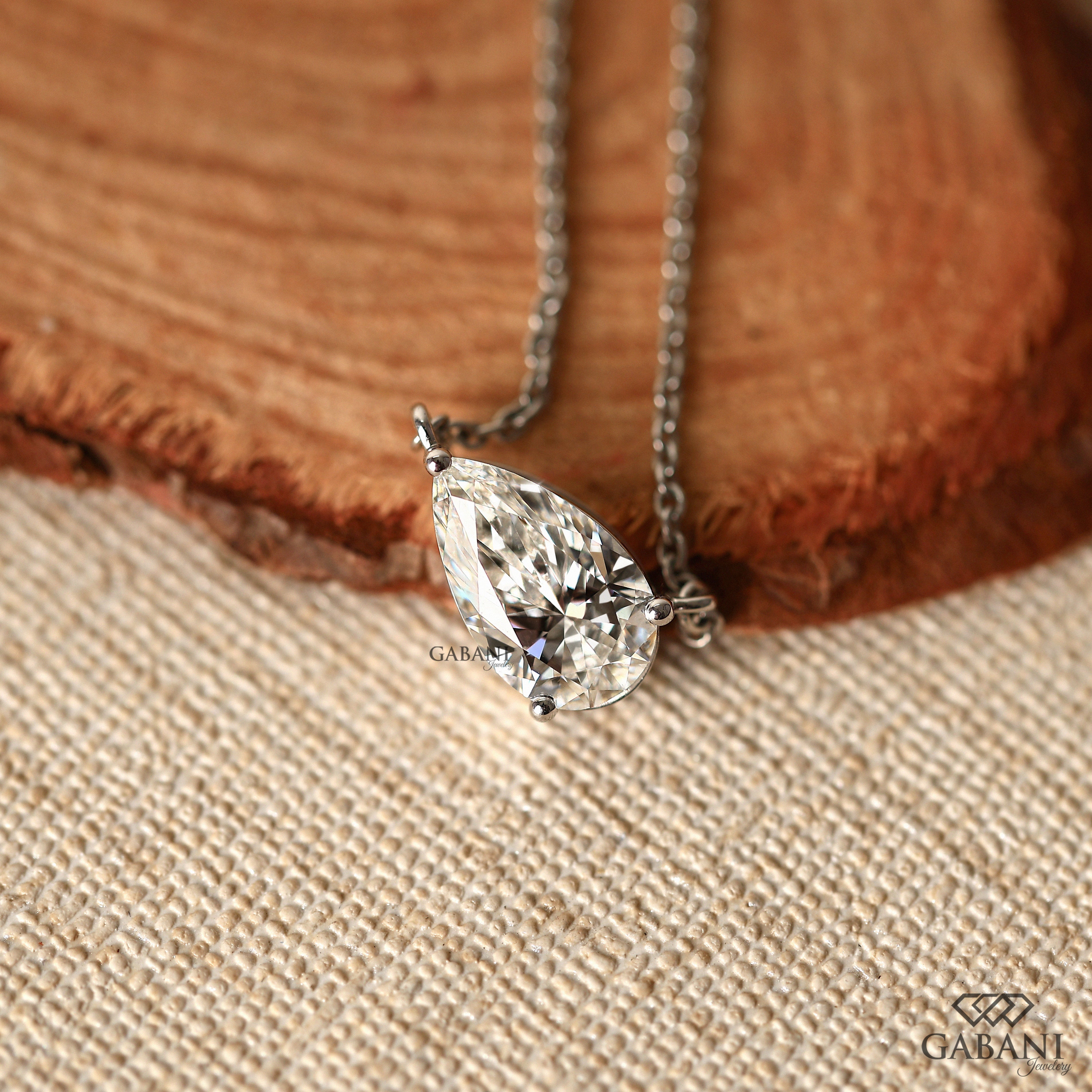 Diamond necklace on a wooden surface with 'GABANI' branding.