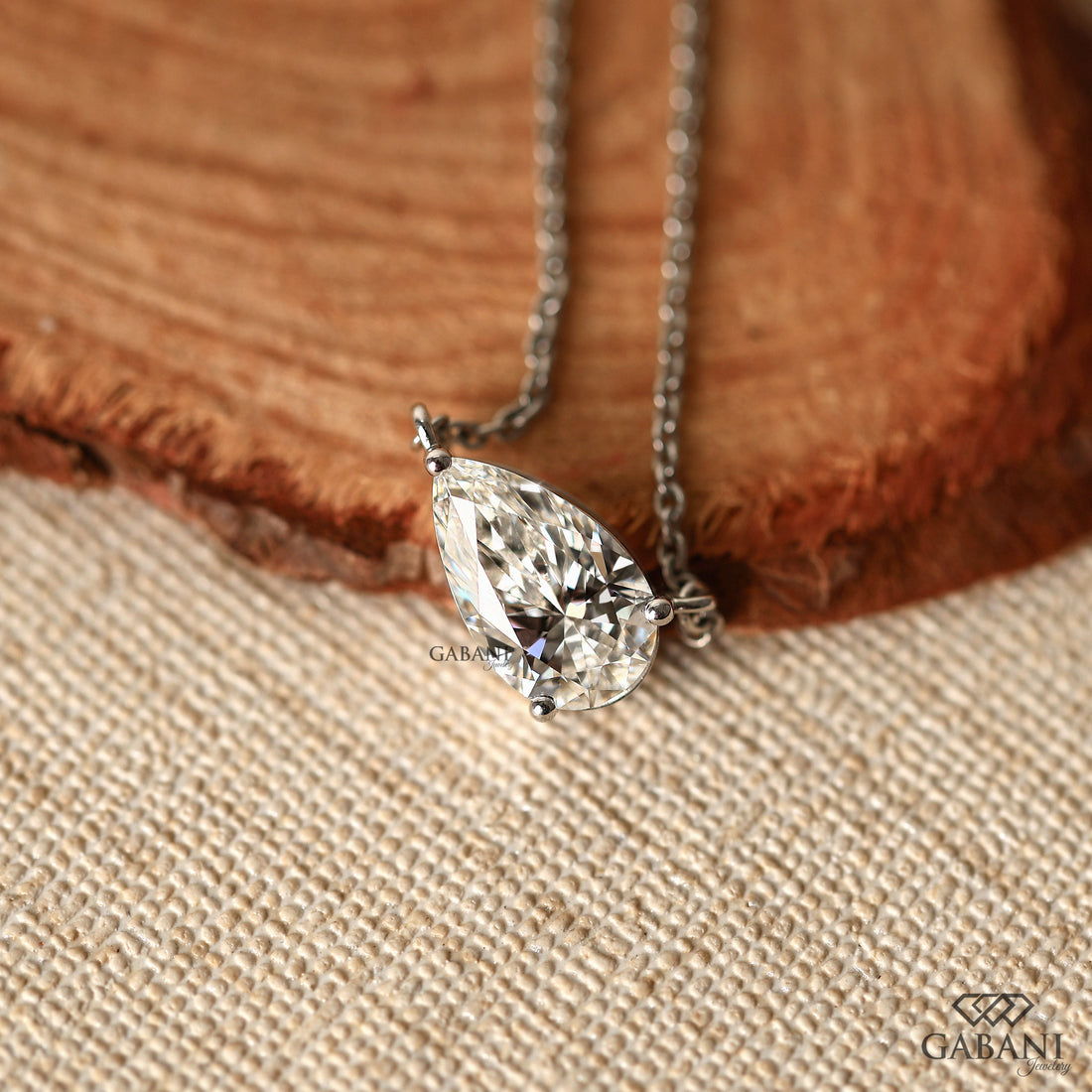 Diamond necklace on a wooden surface with 'GABANI' branding.