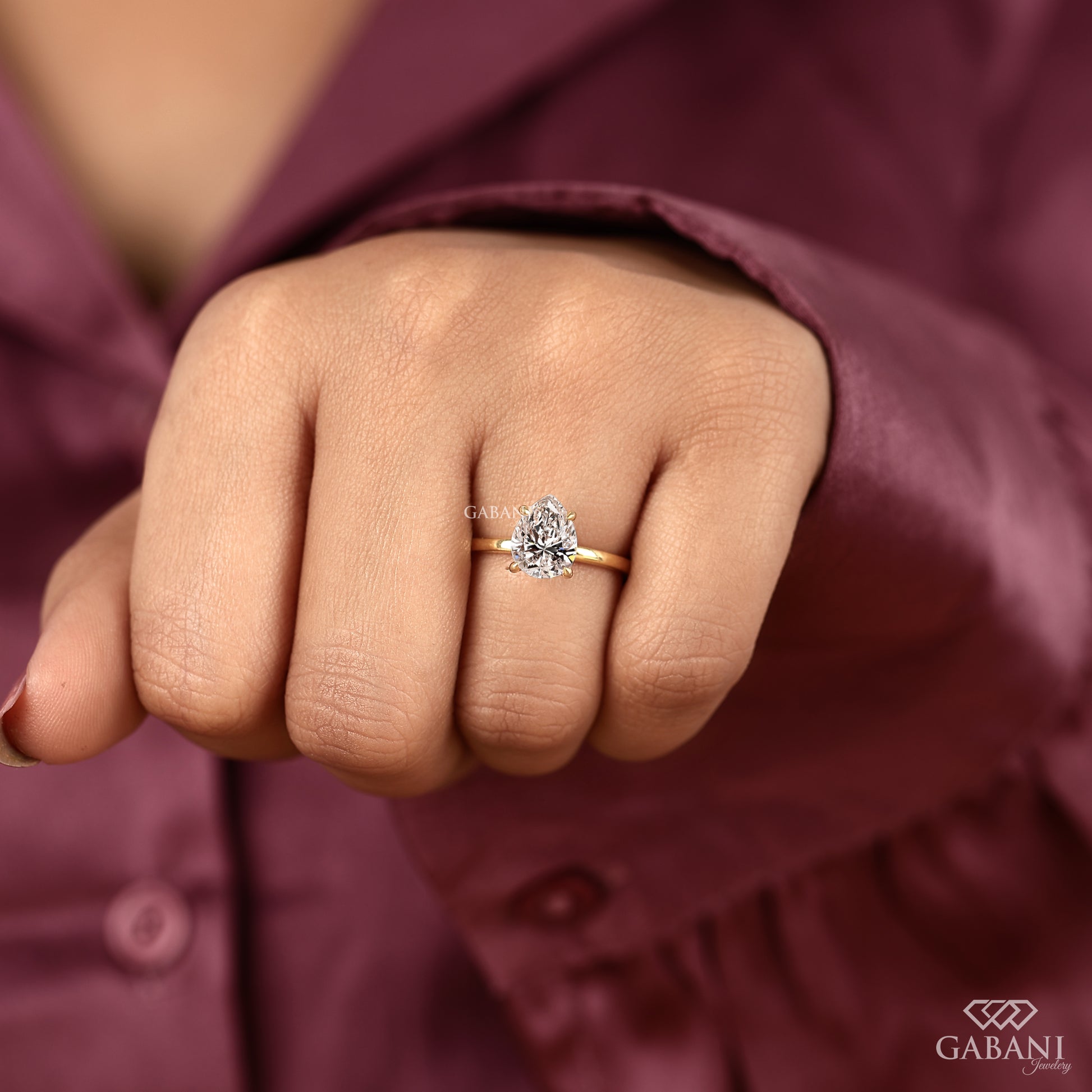 pear cut lab grown diamond solitaire ring with a smooth yellow gold band
