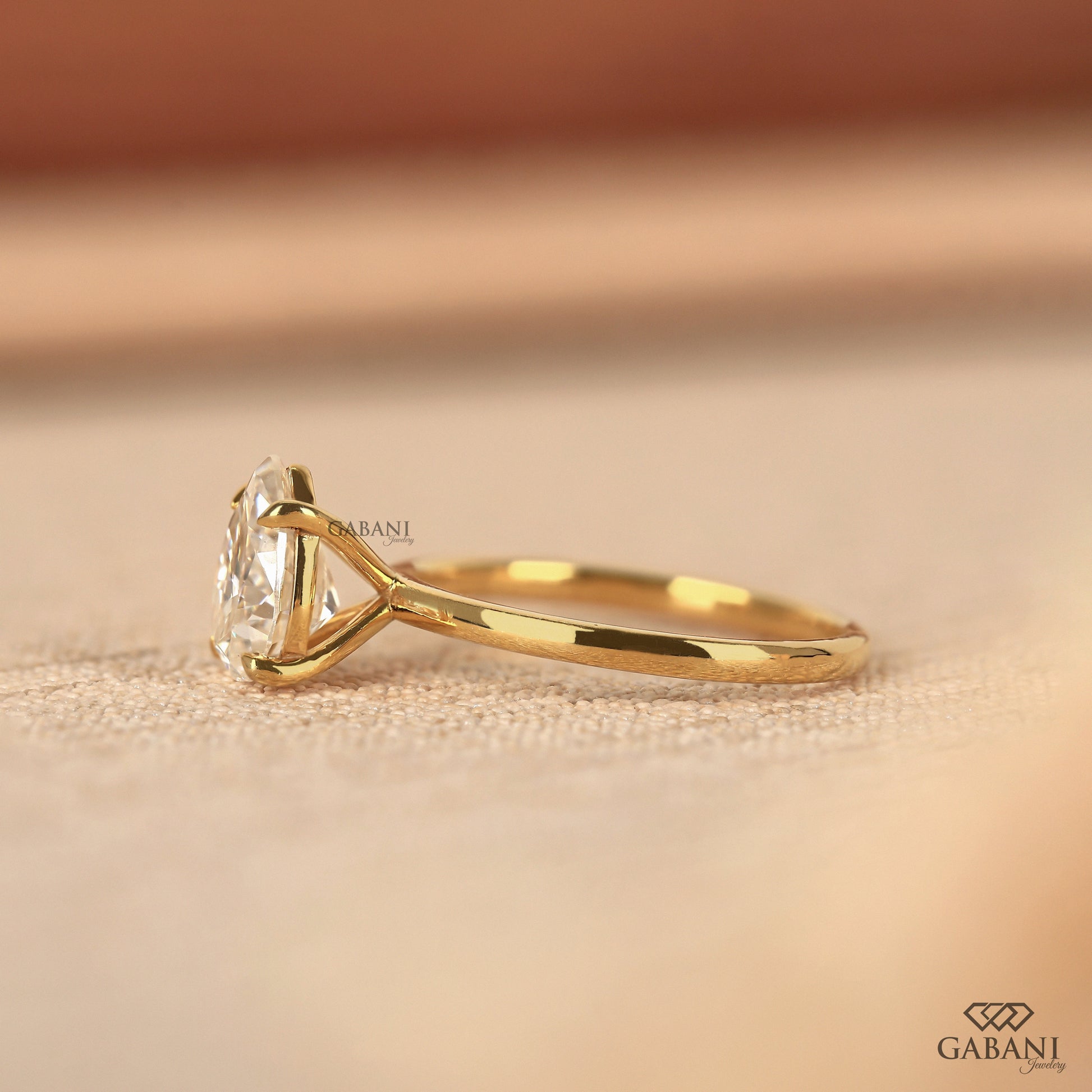 solid yellow gold solitaire ring featuring a pear cut lab grown diamond
