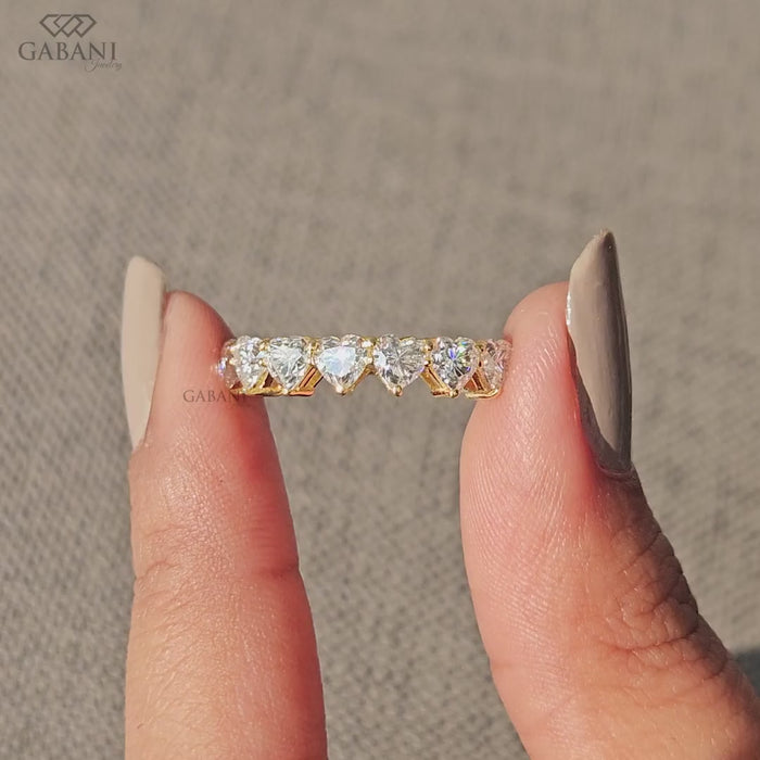 seven heart cut lab grown diamonds in a yellow gold half eternity wedding band with delicate prong settings.
