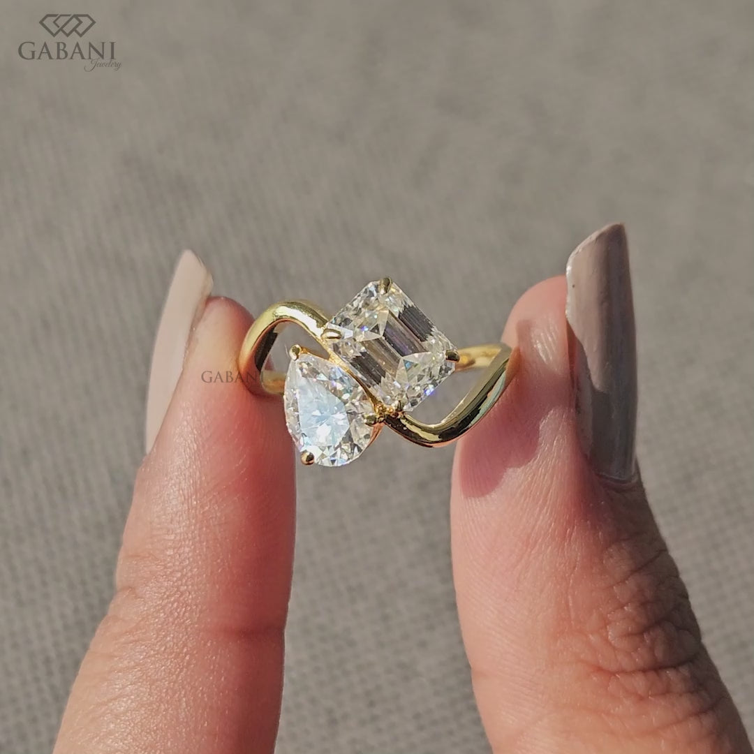 you and me ring featuring emerald and pear cut lab grown diamonds in a yellow gold cross band design