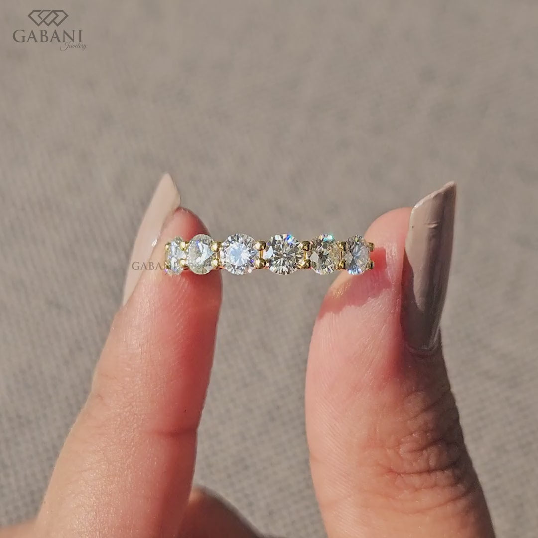 seven round cut lab grown diamonds in a yellow gold half eternity wedding band with open prong settings and a smooth shank.