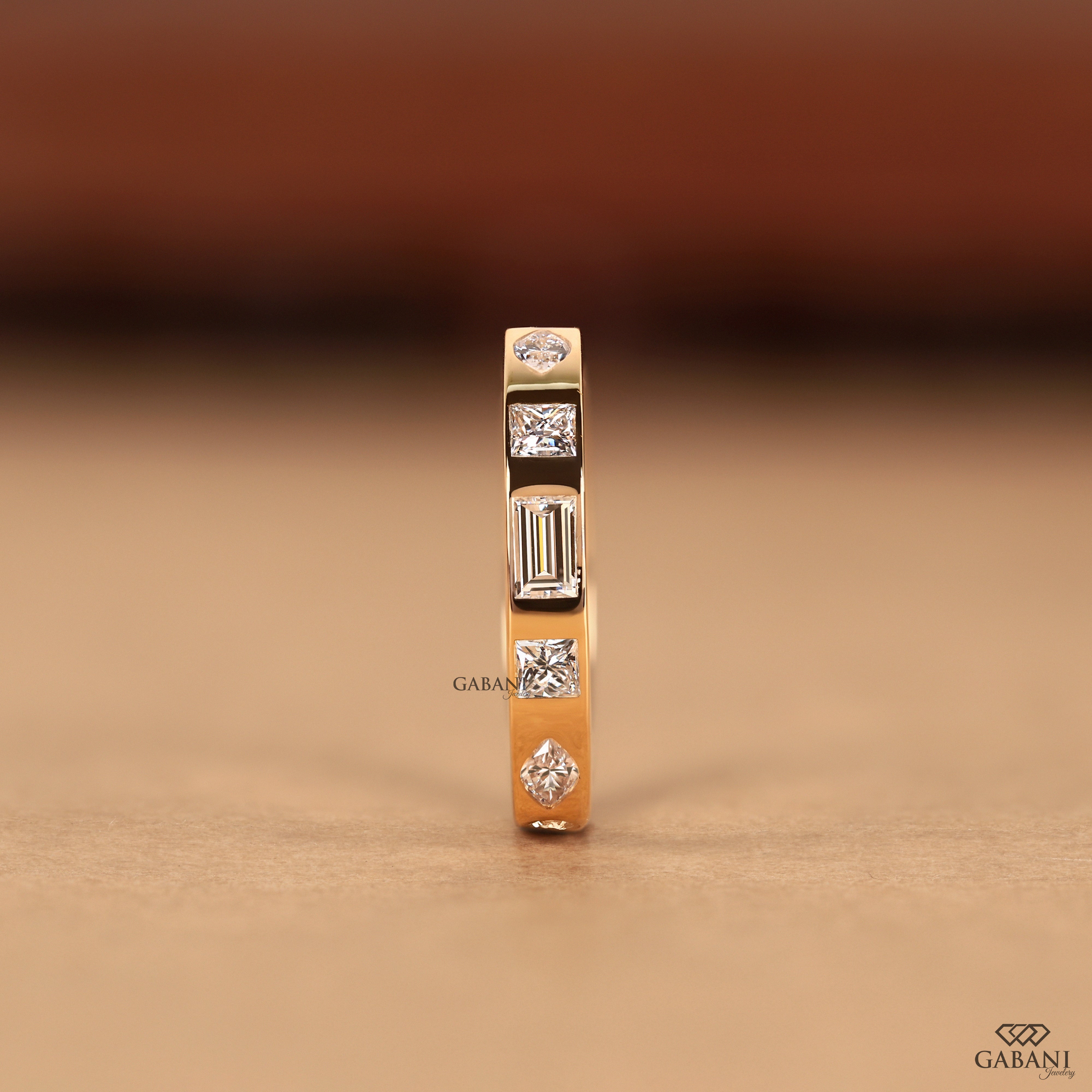 Solid 14K yellow gold flush set wedding ring featuring princess, baguette, round, and marquise lab grown diamonds with a low profile flat band.
