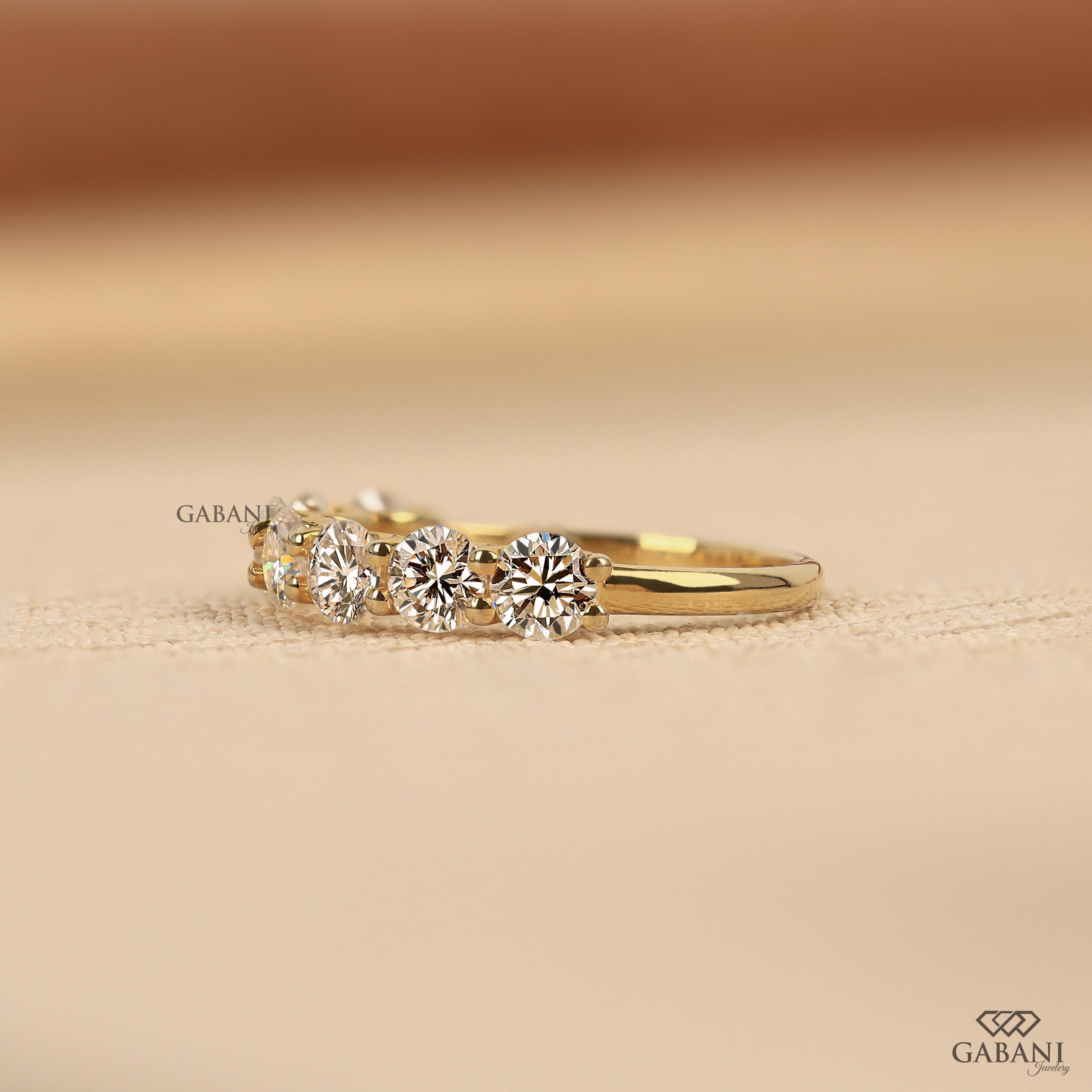 seven round cut lab grown diamonds in a yellow gold half eternity wedding band with open prong settings and a smooth shank.