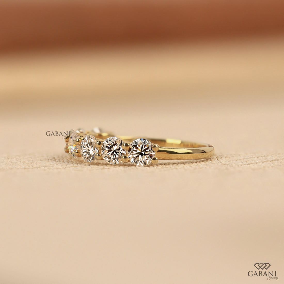 seven round cut lab grown diamonds in a yellow gold half eternity wedding band with open prong settings and a smooth shank.