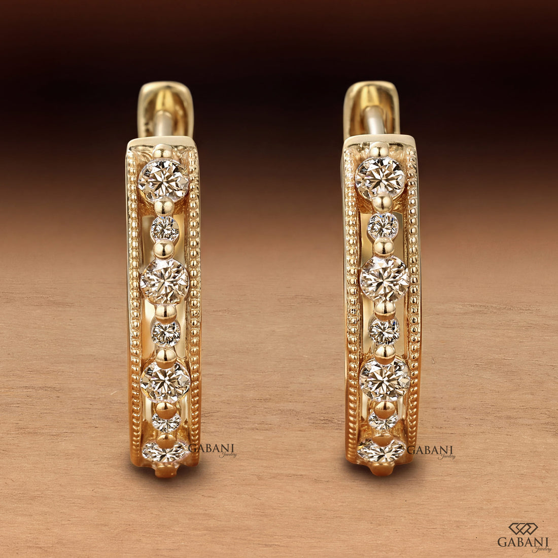 Round cut diamond milgrain hoop earrings in yellow gold with graduated diamonds and beaded edge detailing.