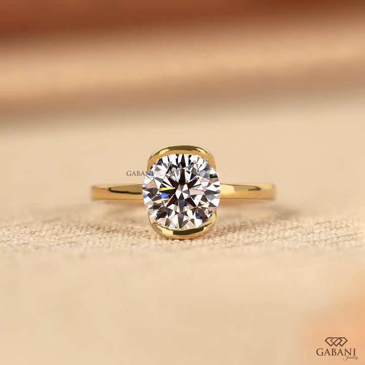 Round diamond half bezel solitaire engagement ring in yellow gold with a slim straight polished band.