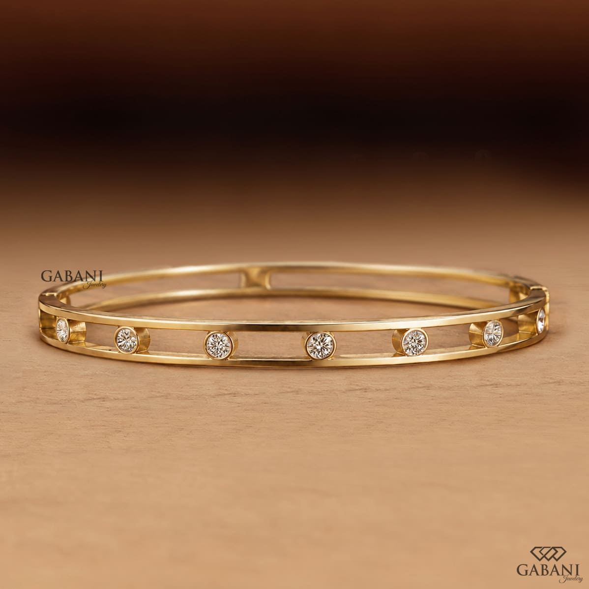 a round lab grown diamond bangle bracelet in yellow gold, featuring evenly spaced bezel set diamonds between two polished gold rails in a modern open-frame design by Gabani Jewelry.