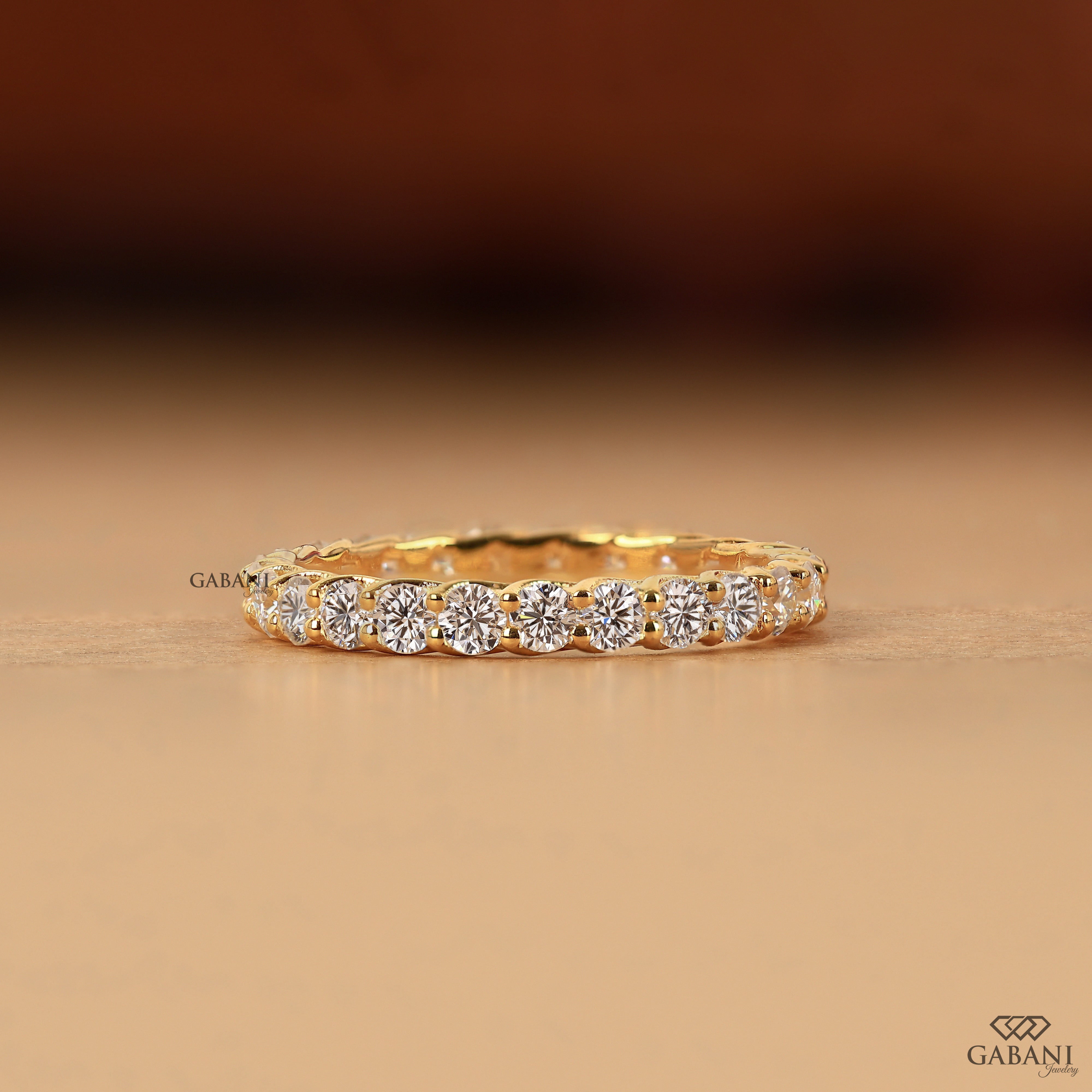 a round lab grown diamond full eternity band in 14K yellow gold, featuring sparkling shared prong set diamonds in a classic wedding band design by Gabani Jewelry.