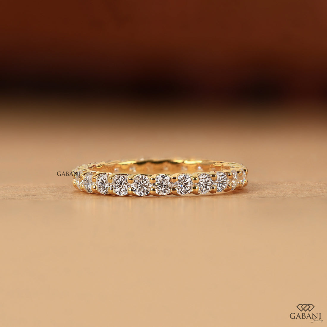 a round lab grown diamond full eternity band in 14K yellow gold, featuring sparkling shared prong set diamonds in a classic wedding band design by Gabani Jewelry.