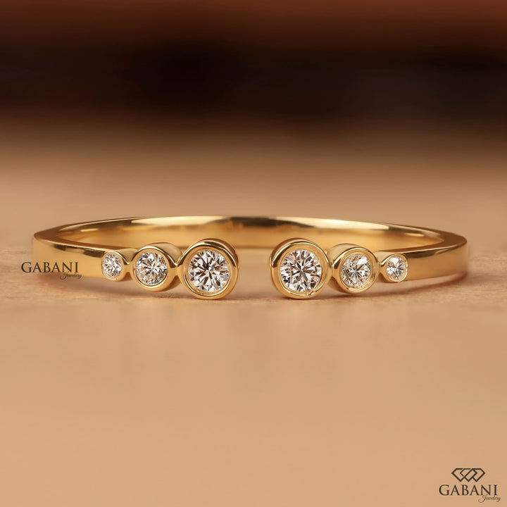 a round cut lab grown diamond open cuff band featuring six graduated bezel set diamonds in polished 14K yellow gold, a modern minimalist diamond wedding band by Gabani Jewelry.