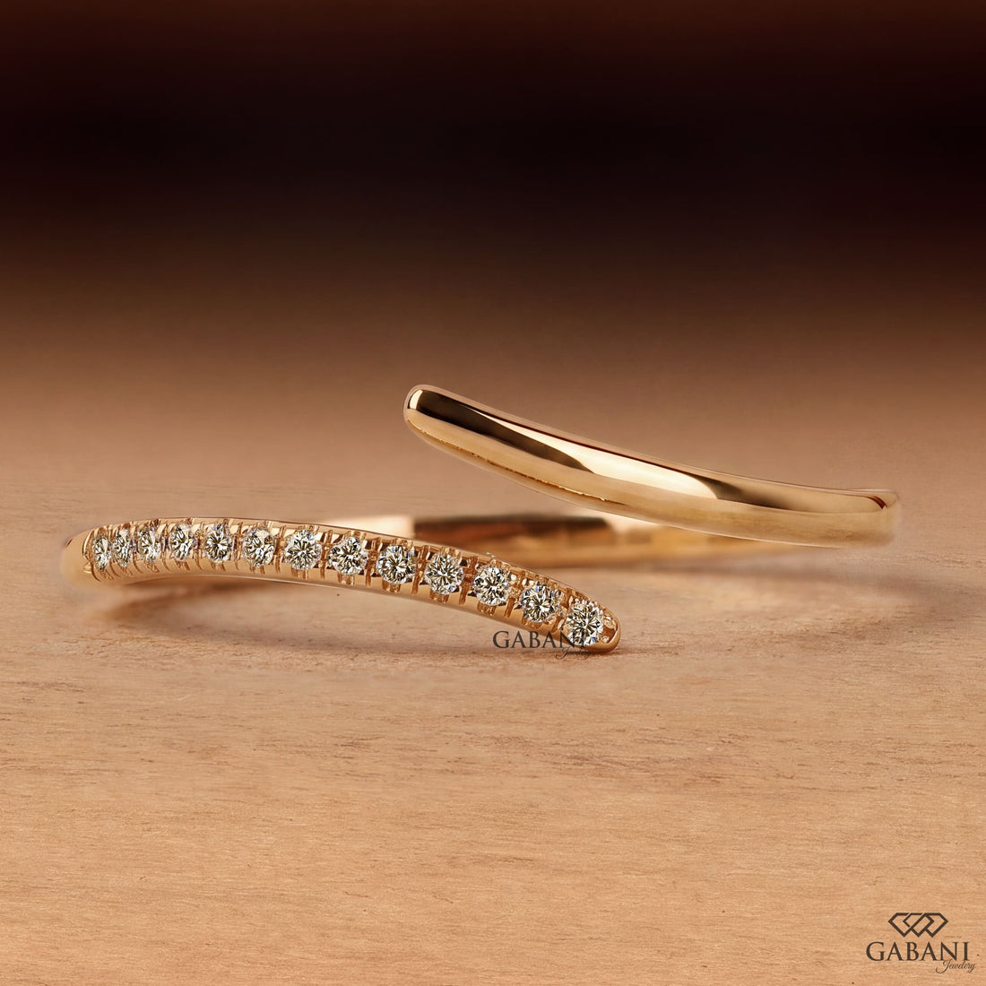 a round lab grown diamond open cuff bangle bracelet in 14K yellow gold, featuring sparkling round diamonds along one curved end and a smooth polished gold wrap design by Gabani Jewelry.